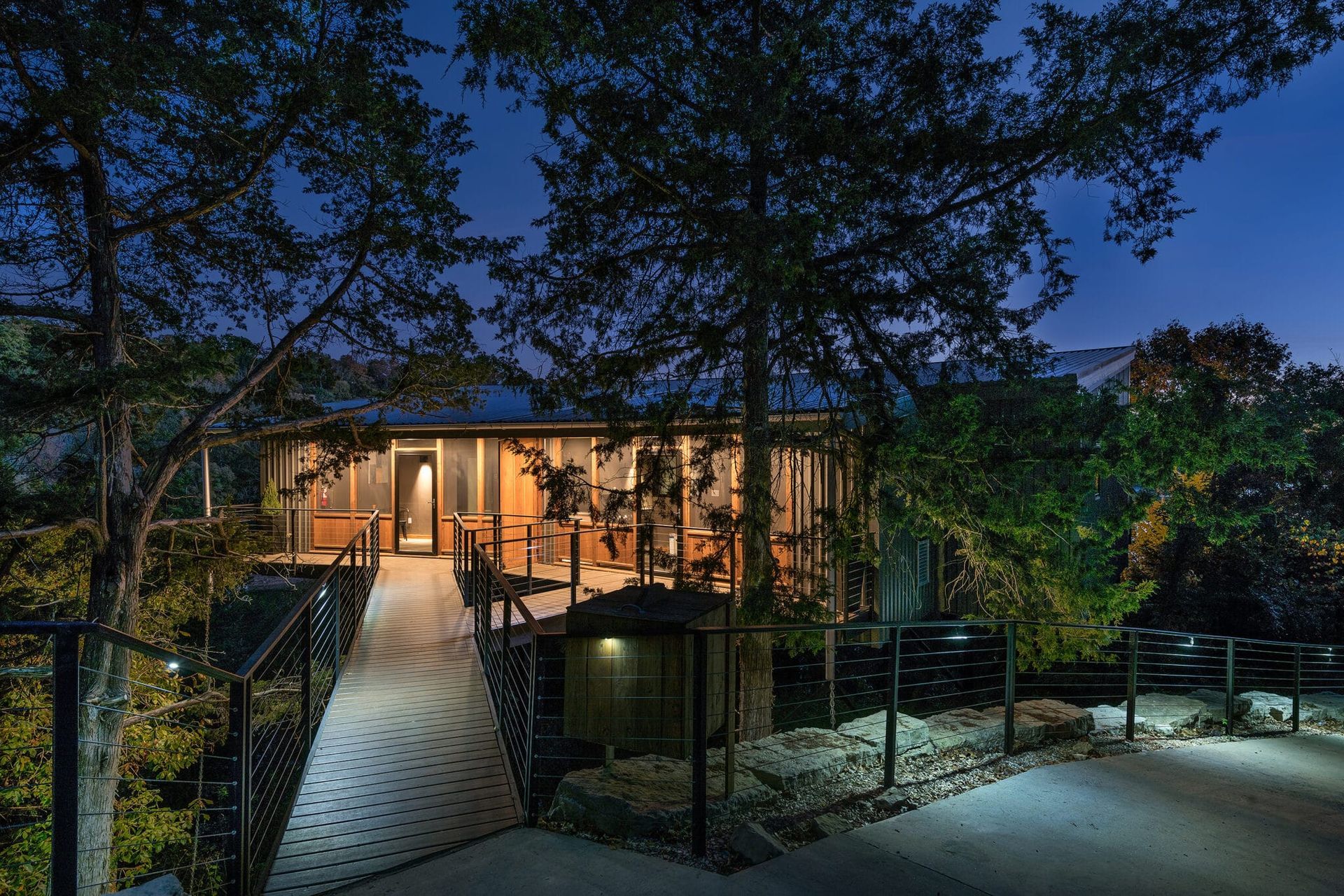 A house with a walkway leading to it at night surrounded by trees.