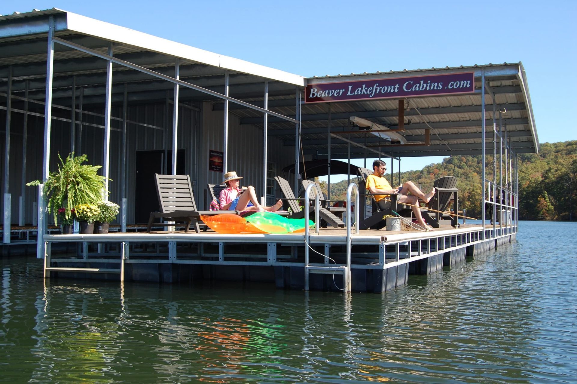 A man and woman are sitting on a dock on a lake.