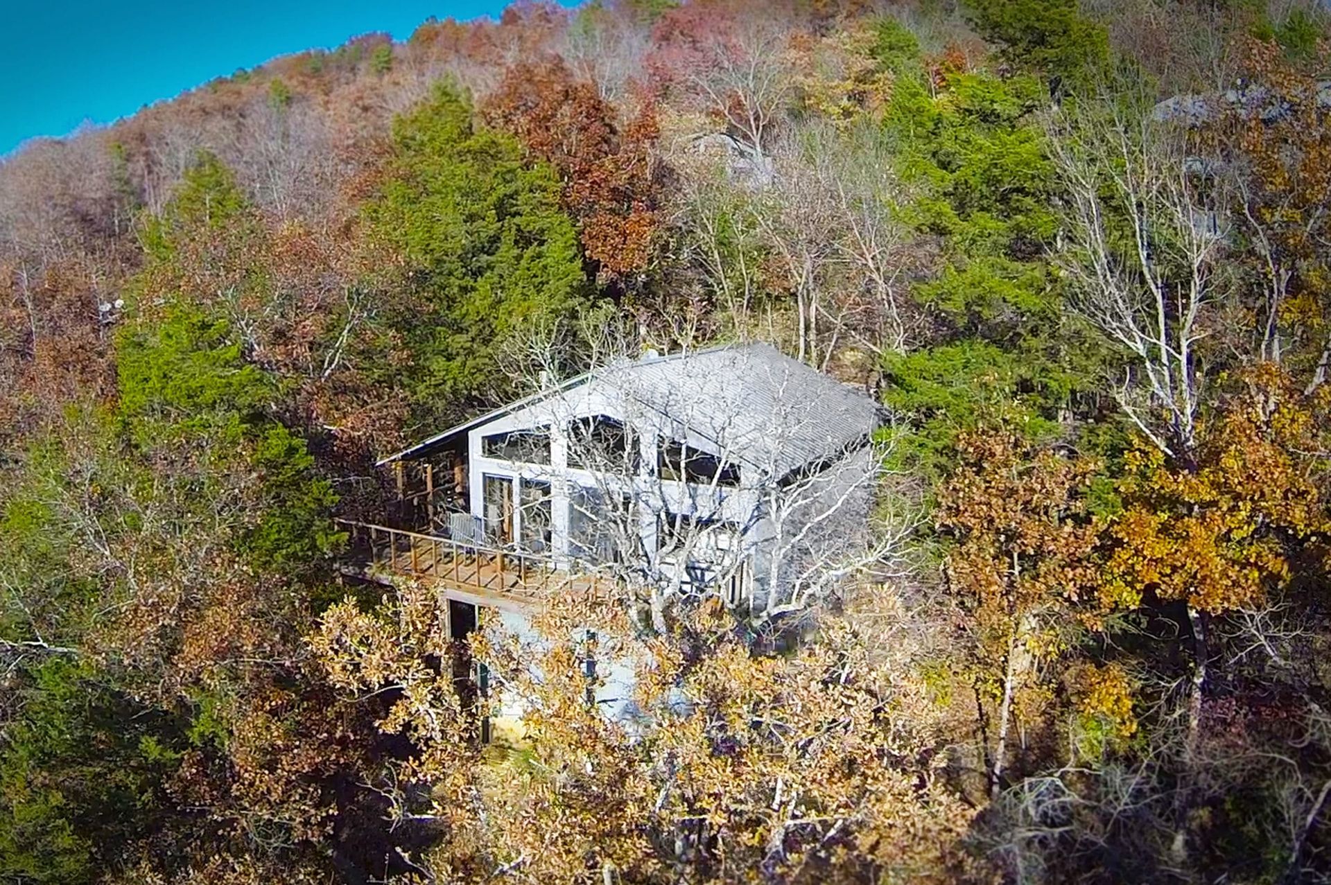 An aerial view of a house on top of a hill surrounded by trees.