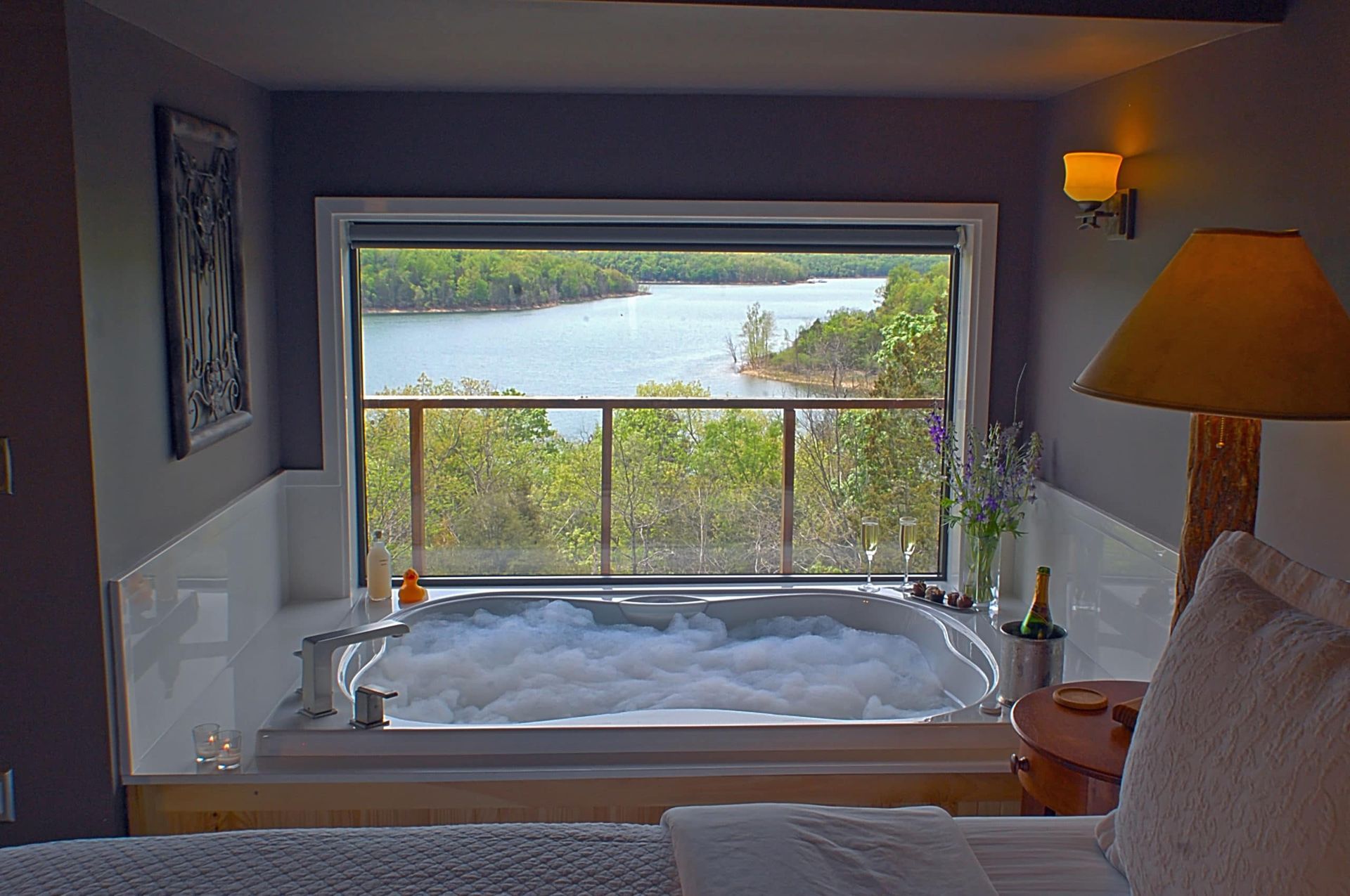 There is a jacuzzi in the middle of the room with a view of a lake.