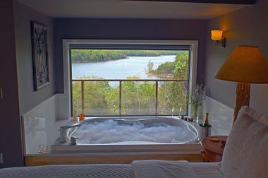 There is a jacuzzi in the middle of the room with a view of a lake.