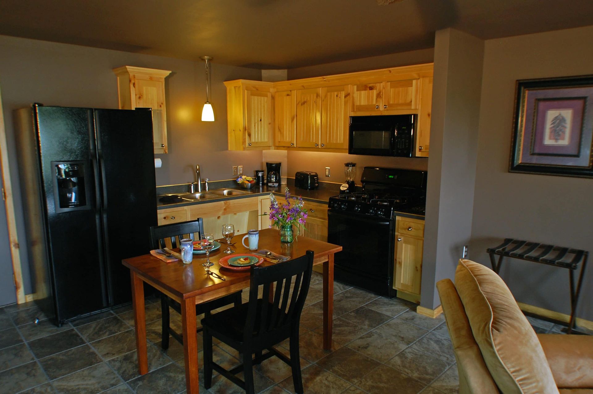 A kitchen with a table and chairs and a black refrigerator