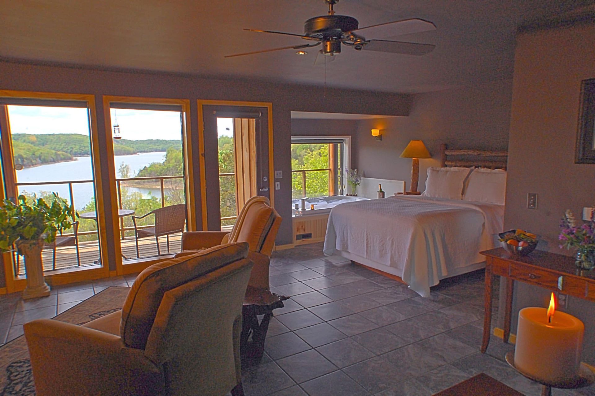 A bedroom with a large bed , a couch , a chair and a ceiling fan.