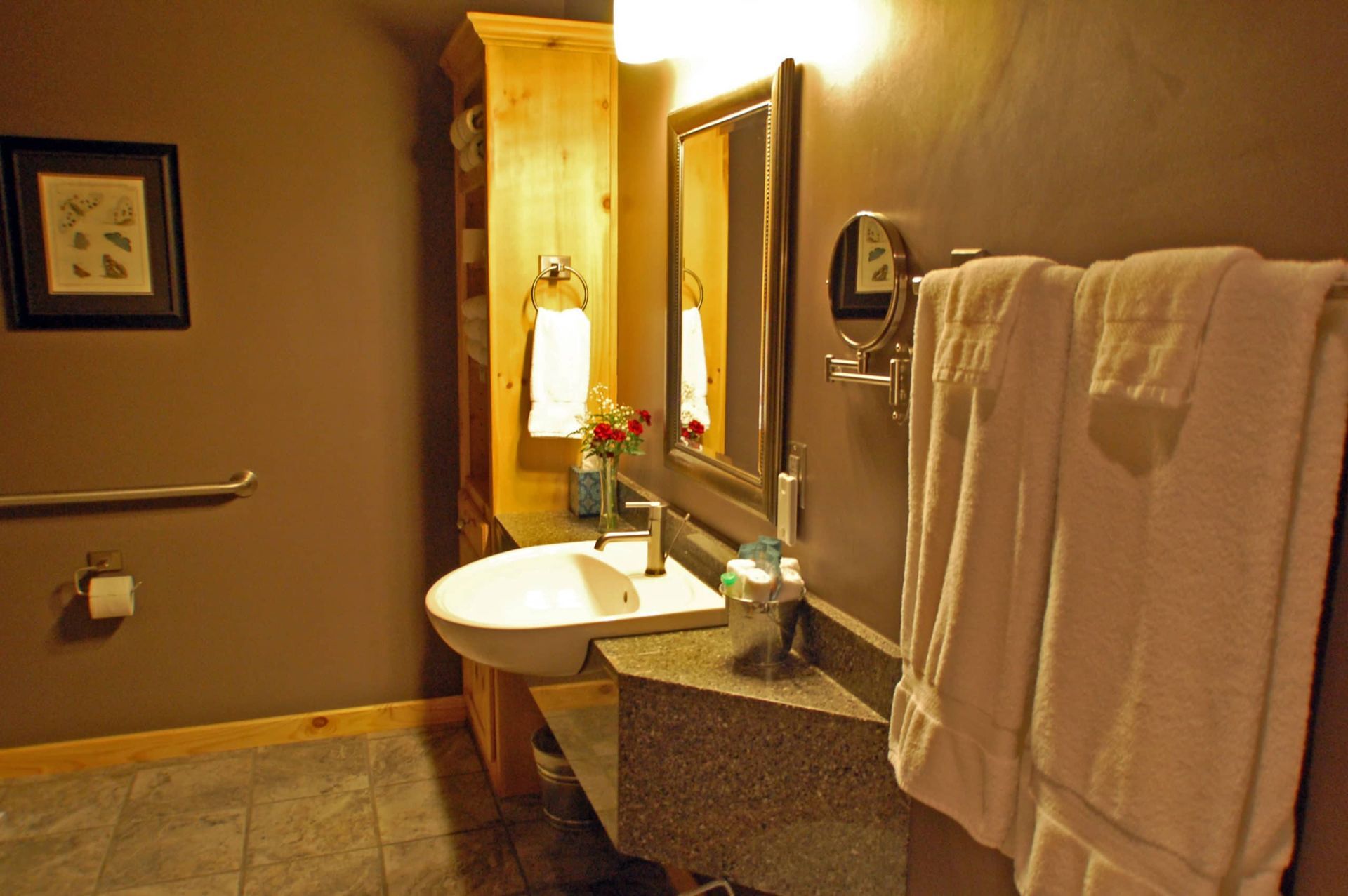 A bathroom with a sink , mirror and towels hanging on the wall.