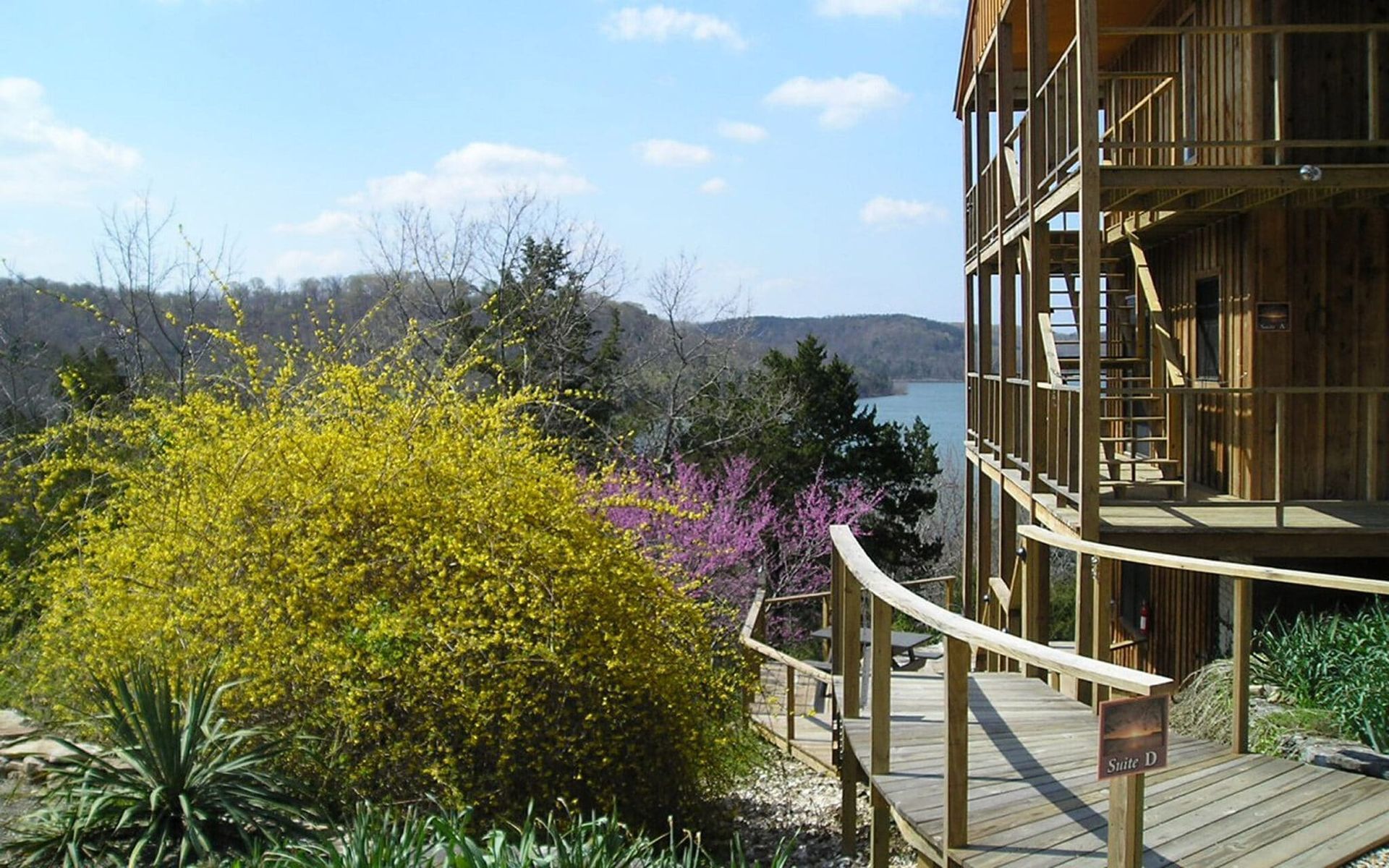 A wooden walkway leading to a house with a lake in the background