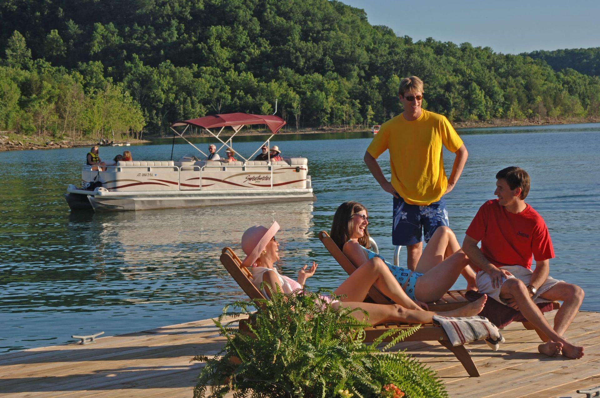 A group of people sitting on a dock with a boat in the background