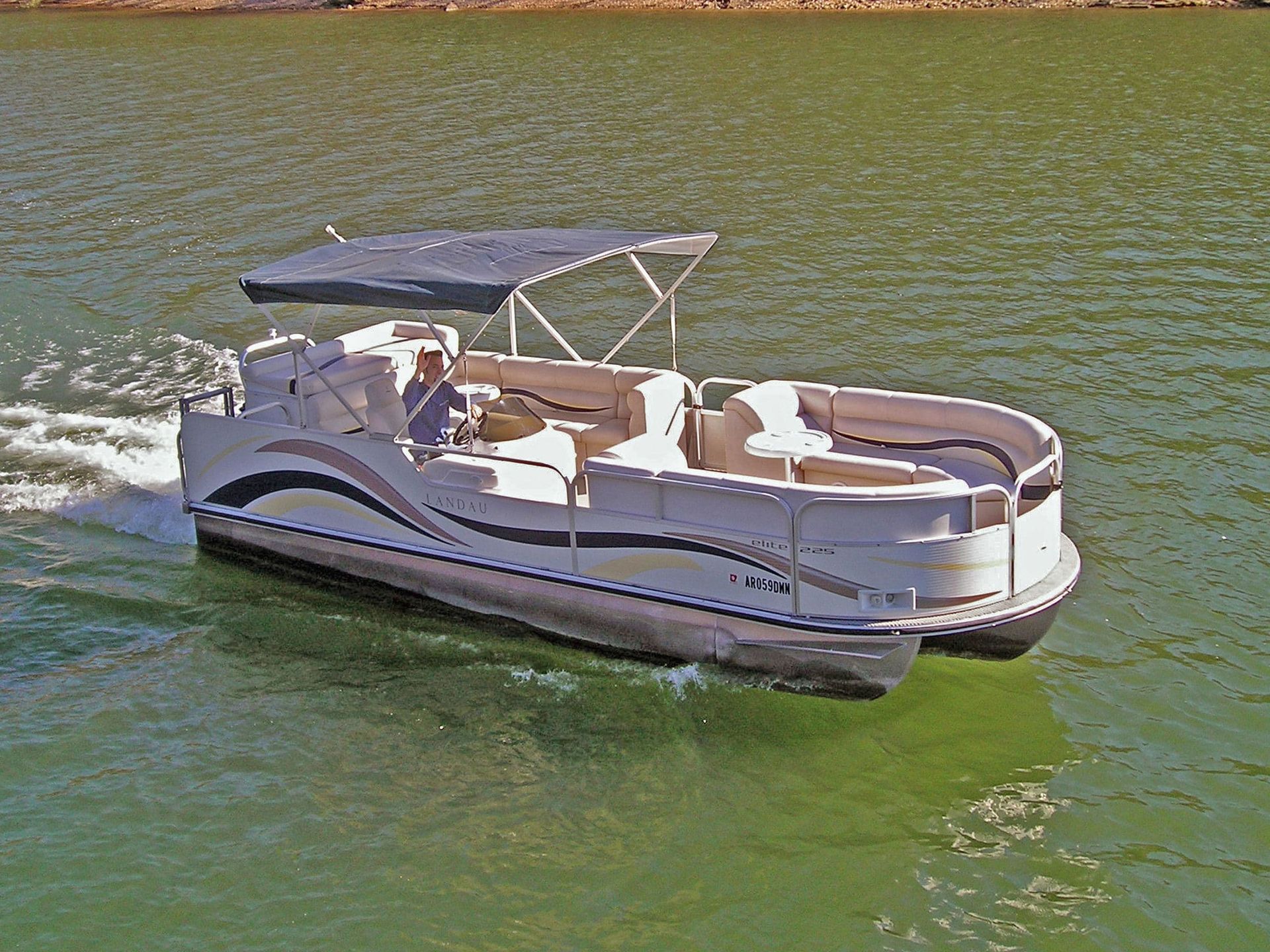 A pontoon boat with a canopy is floating on a lake