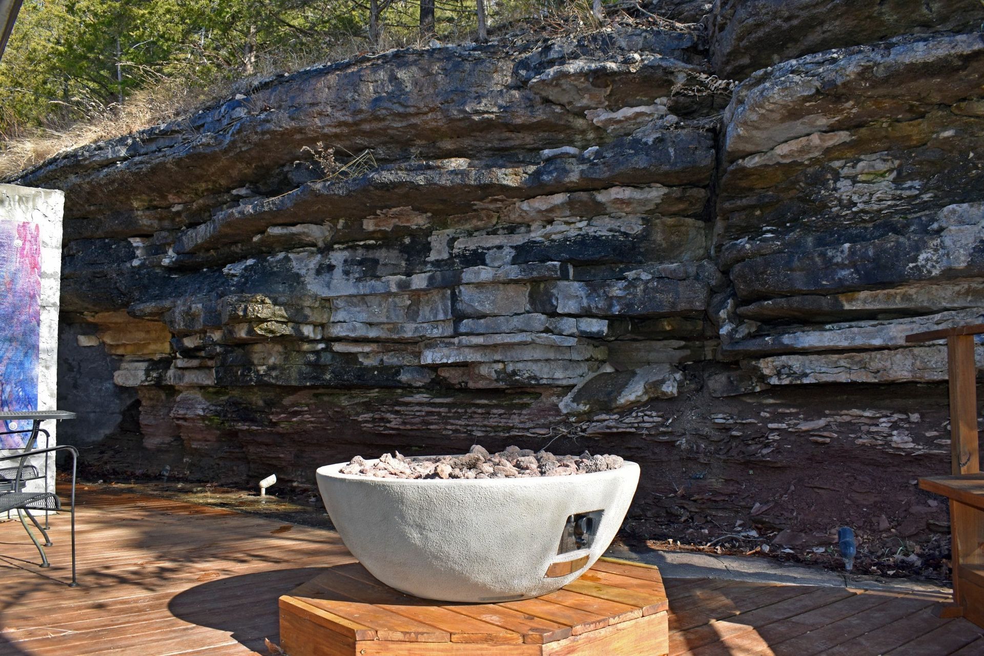 A large coffee cup is sitting on a wooden table in front of a rock wall.