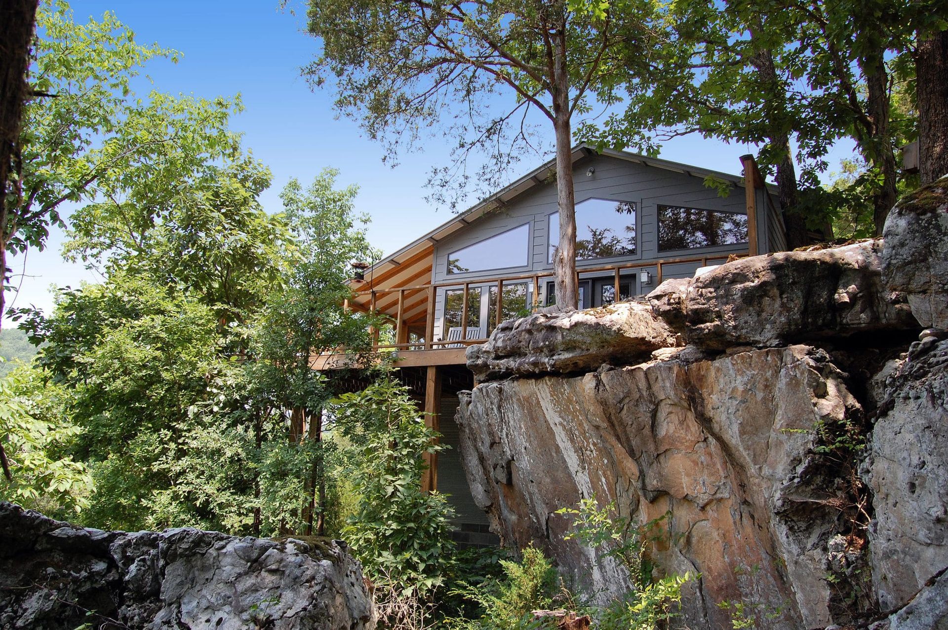 A house sitting on top of a rocky cliff surrounded by trees