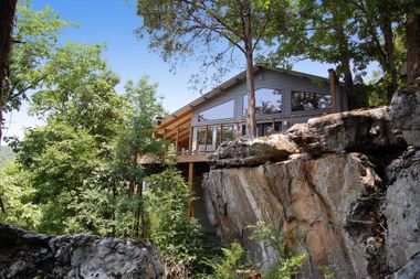 A house sitting on top of a rocky cliff surrounded by trees