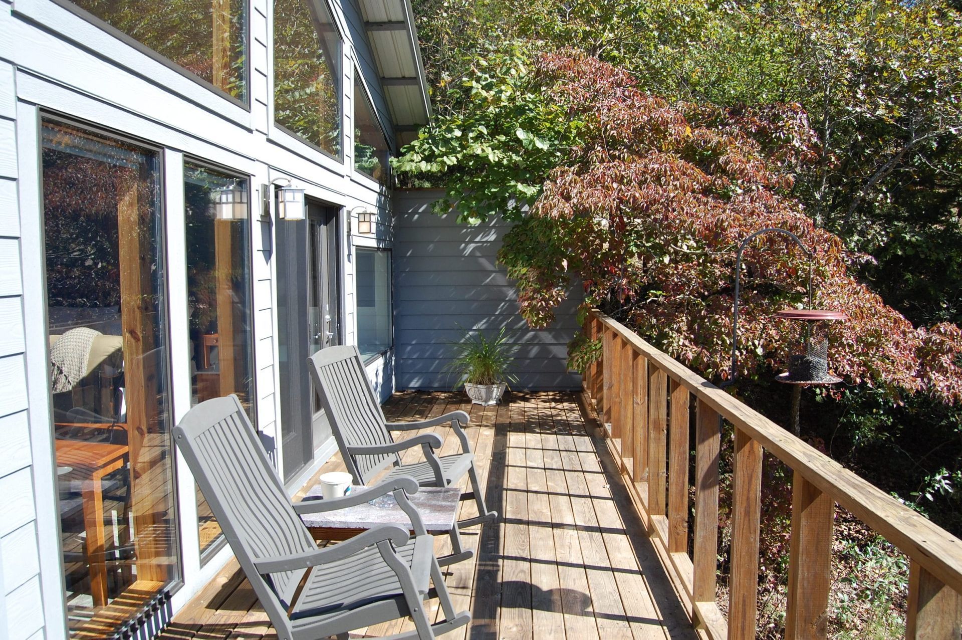 A deck with chairs and a table in front of a house