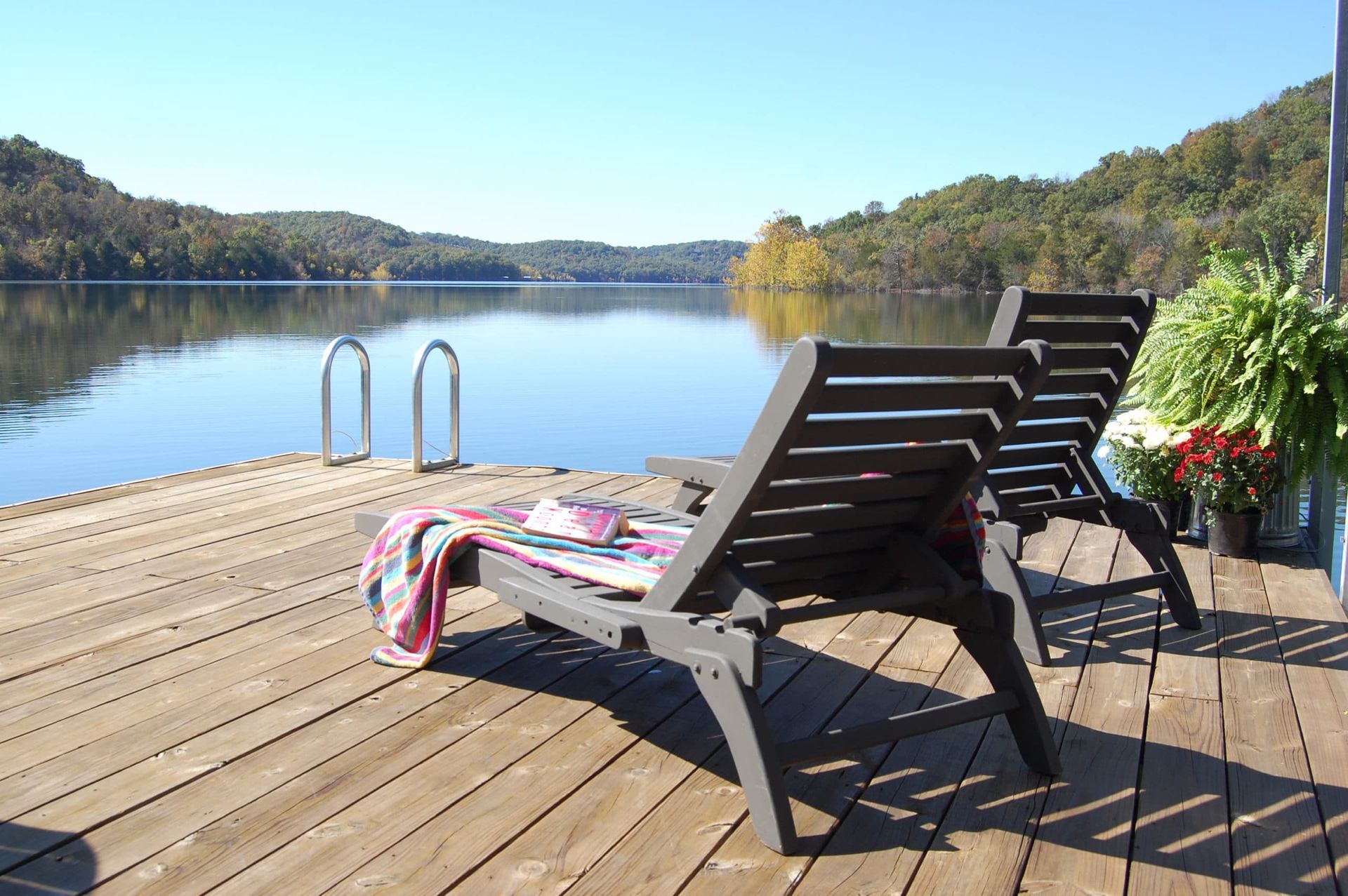 Two lounge chairs on a dock overlooking a lake