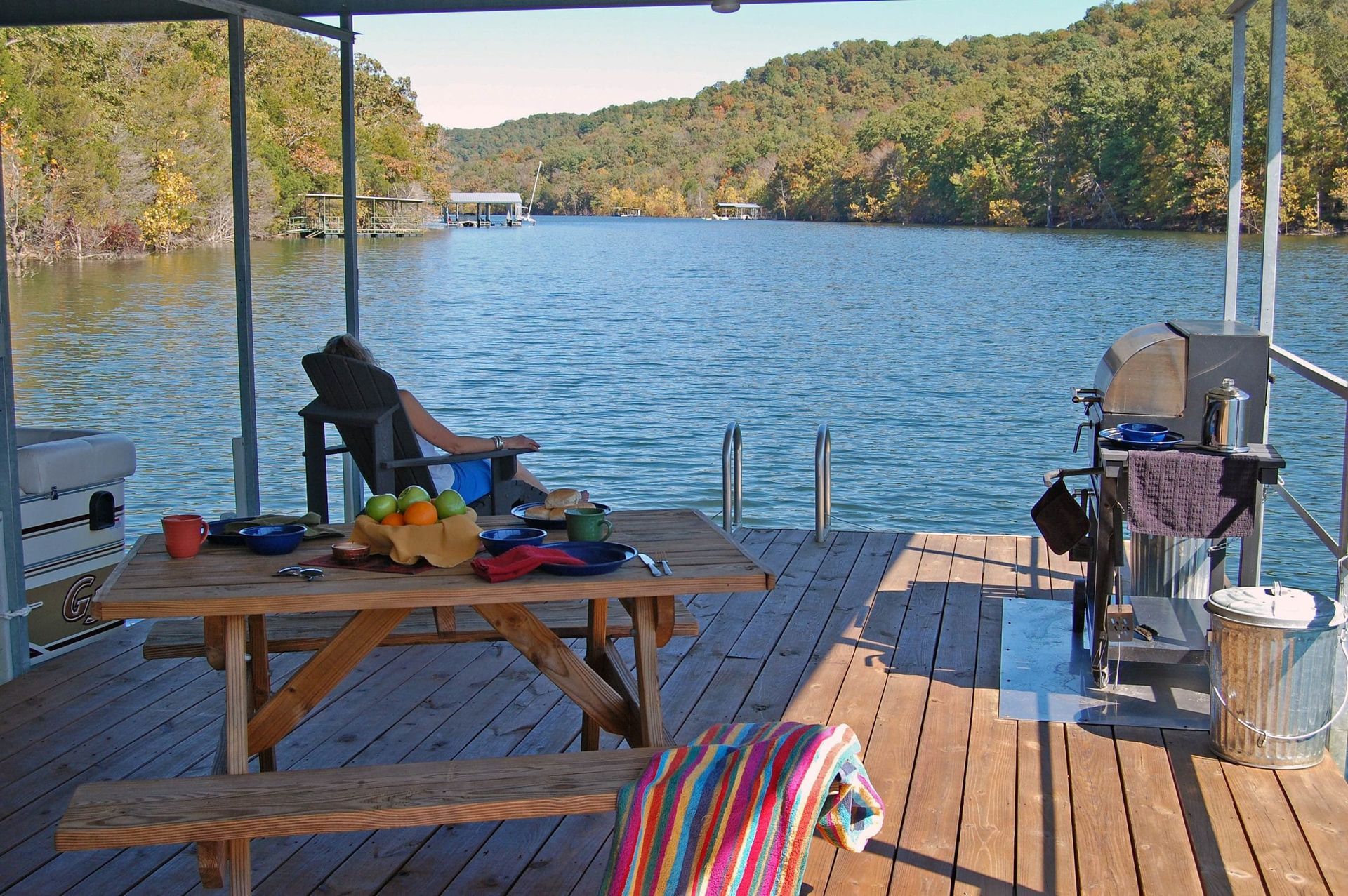 A person sits on a chair on a dock overlooking a lake