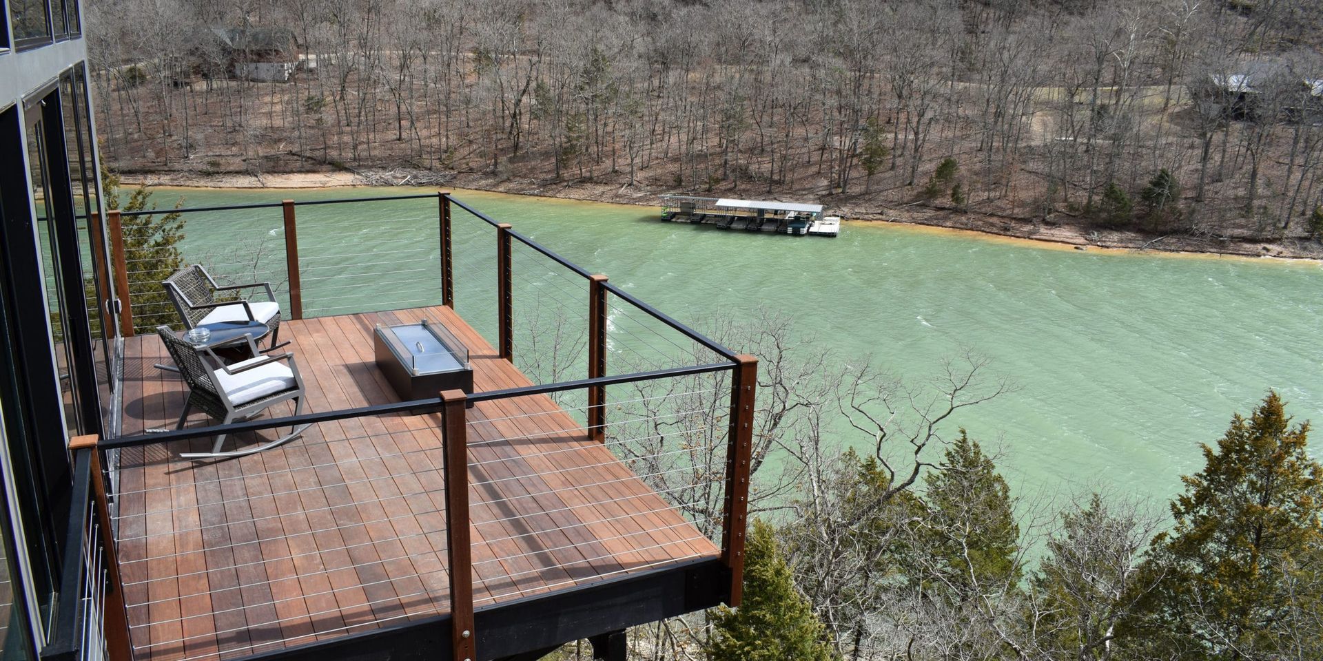 A wooden deck overlooking a lake with a boat in the distance.