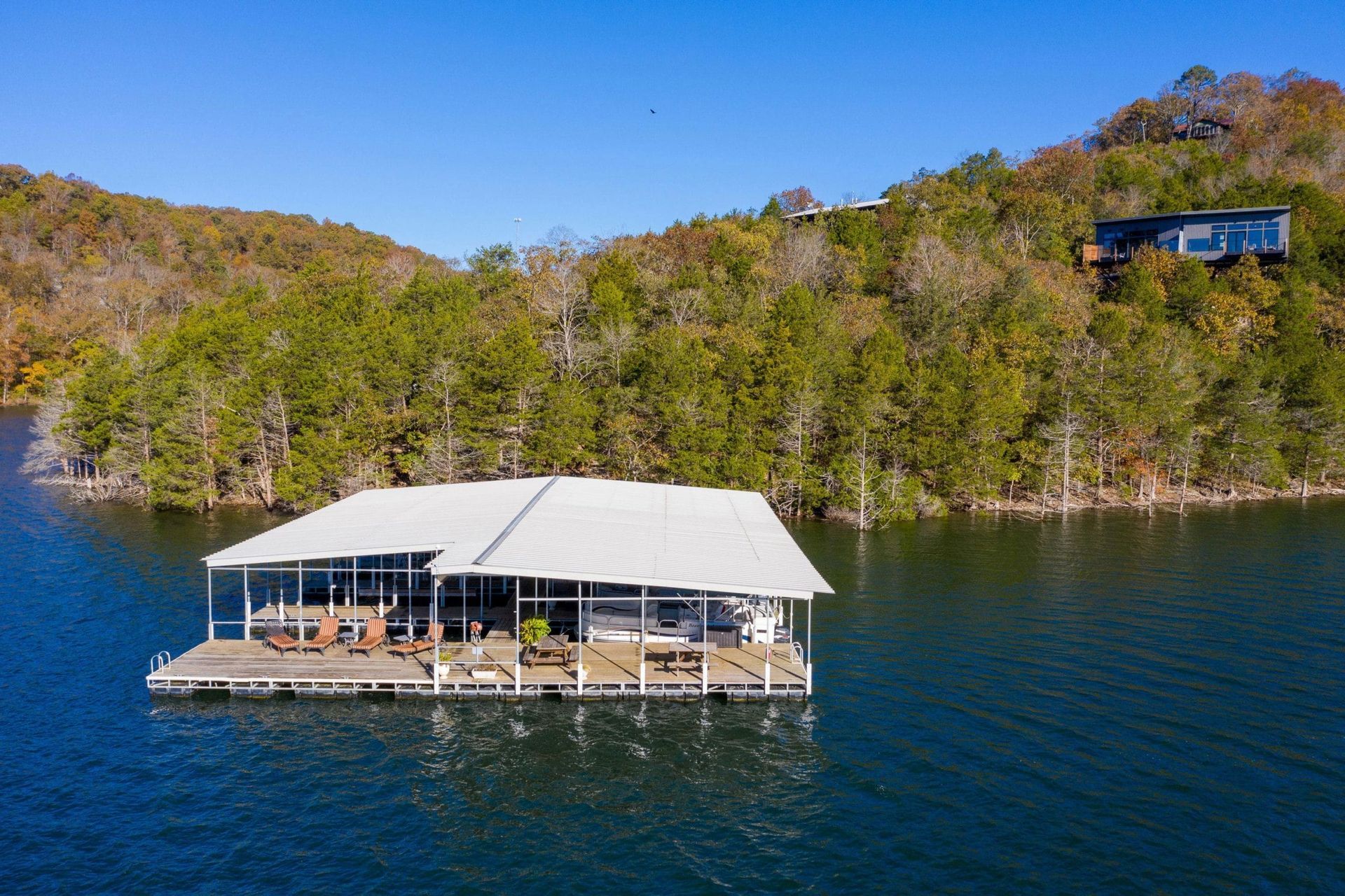 An aerial view of a floating house on a lake surrounded by trees.