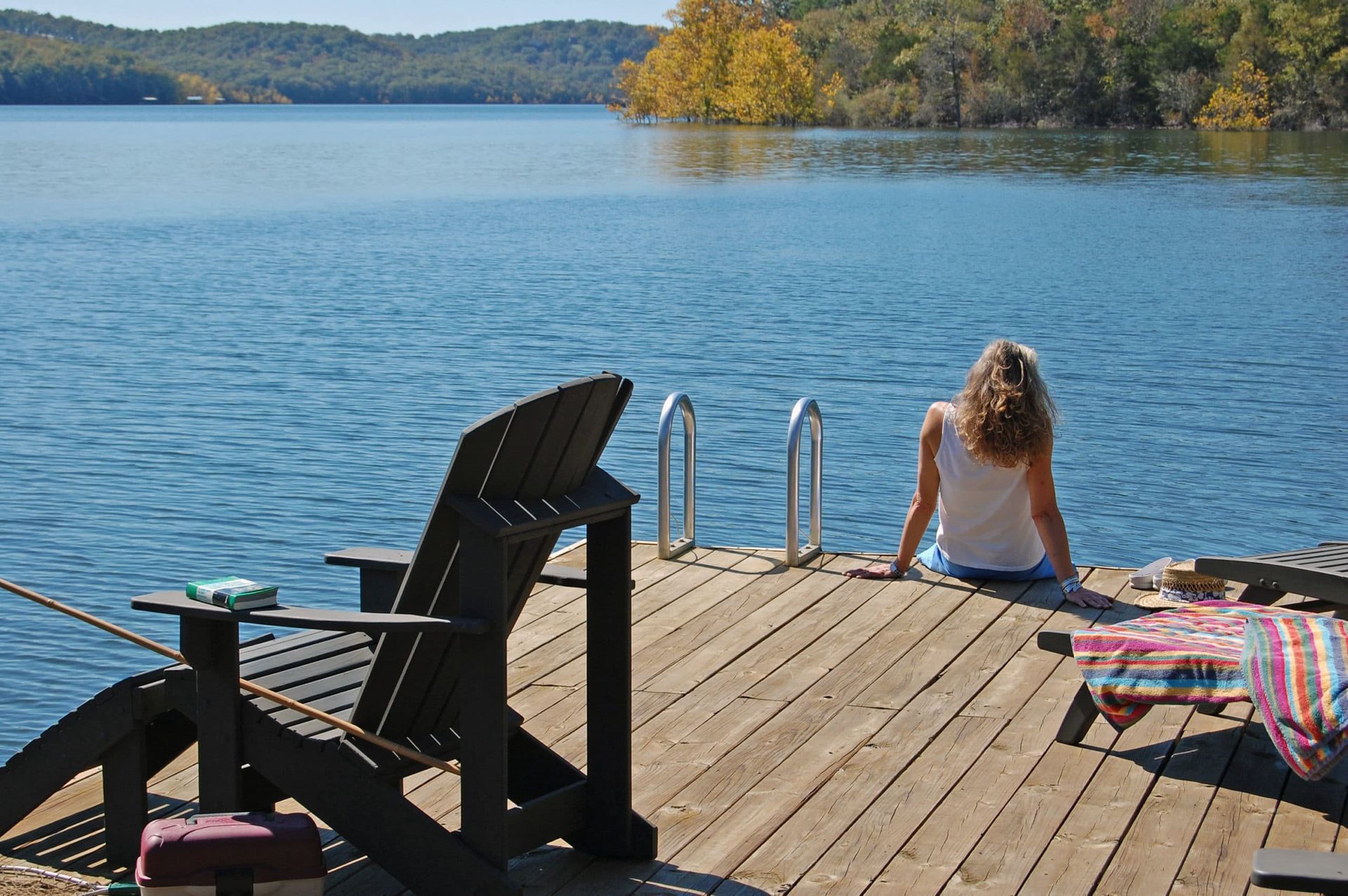 A woman sits on a dock overlooking a lake