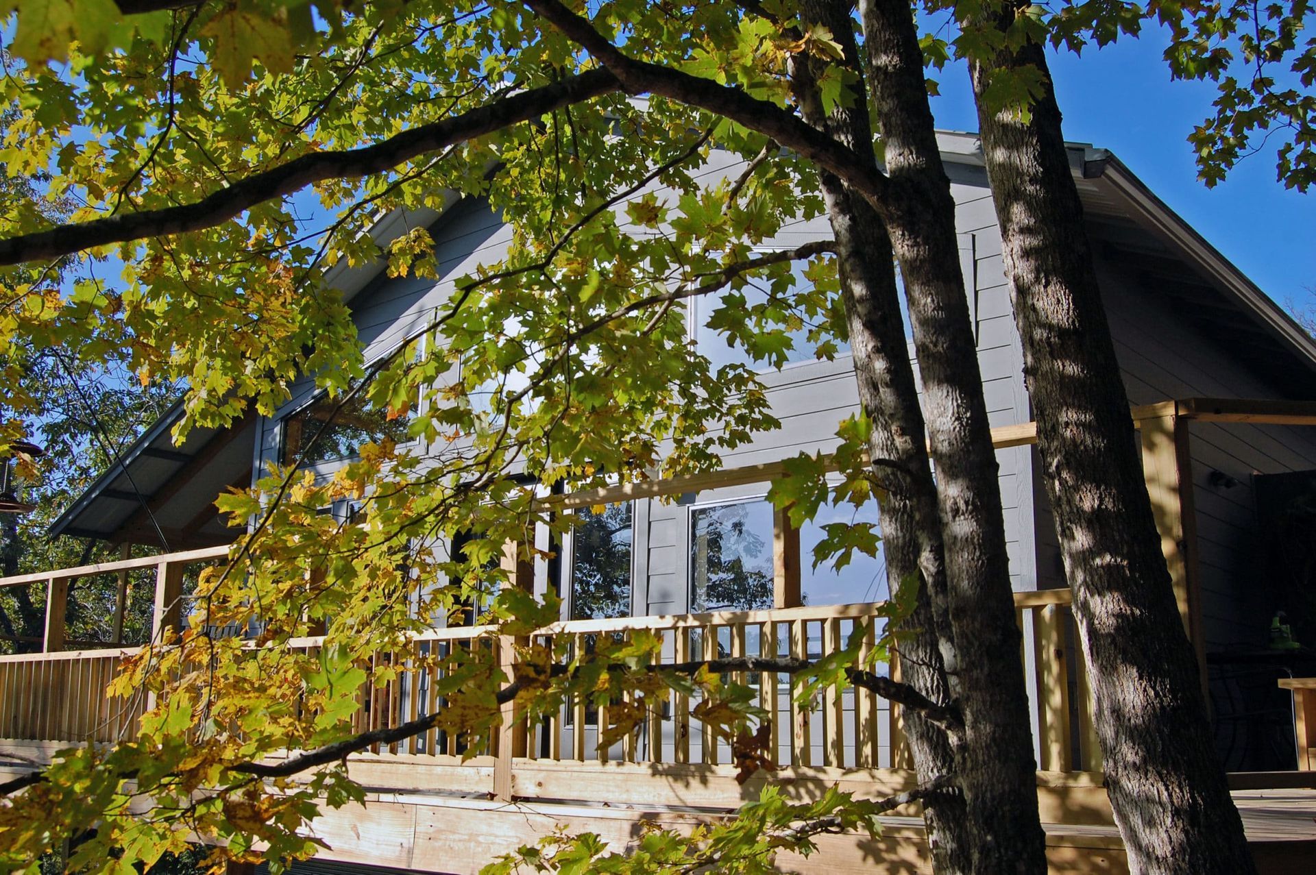 A house with a deck and trees in front of it