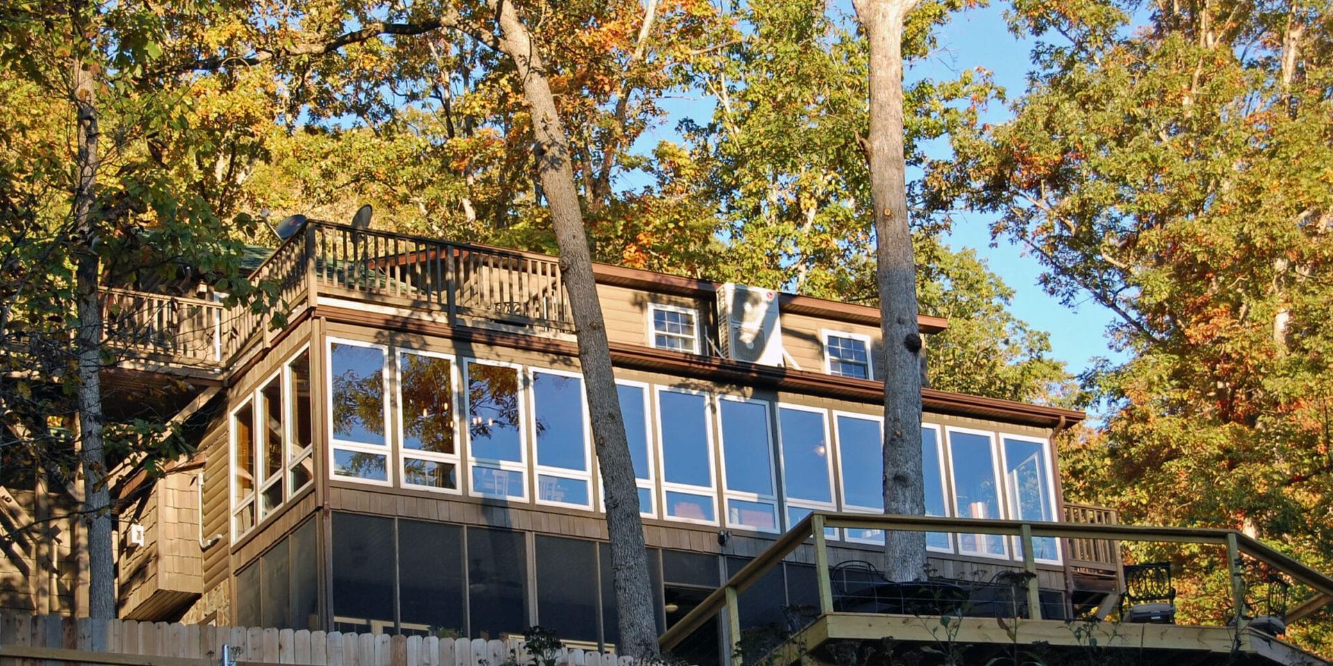A house with a lot of windows is surrounded by trees.