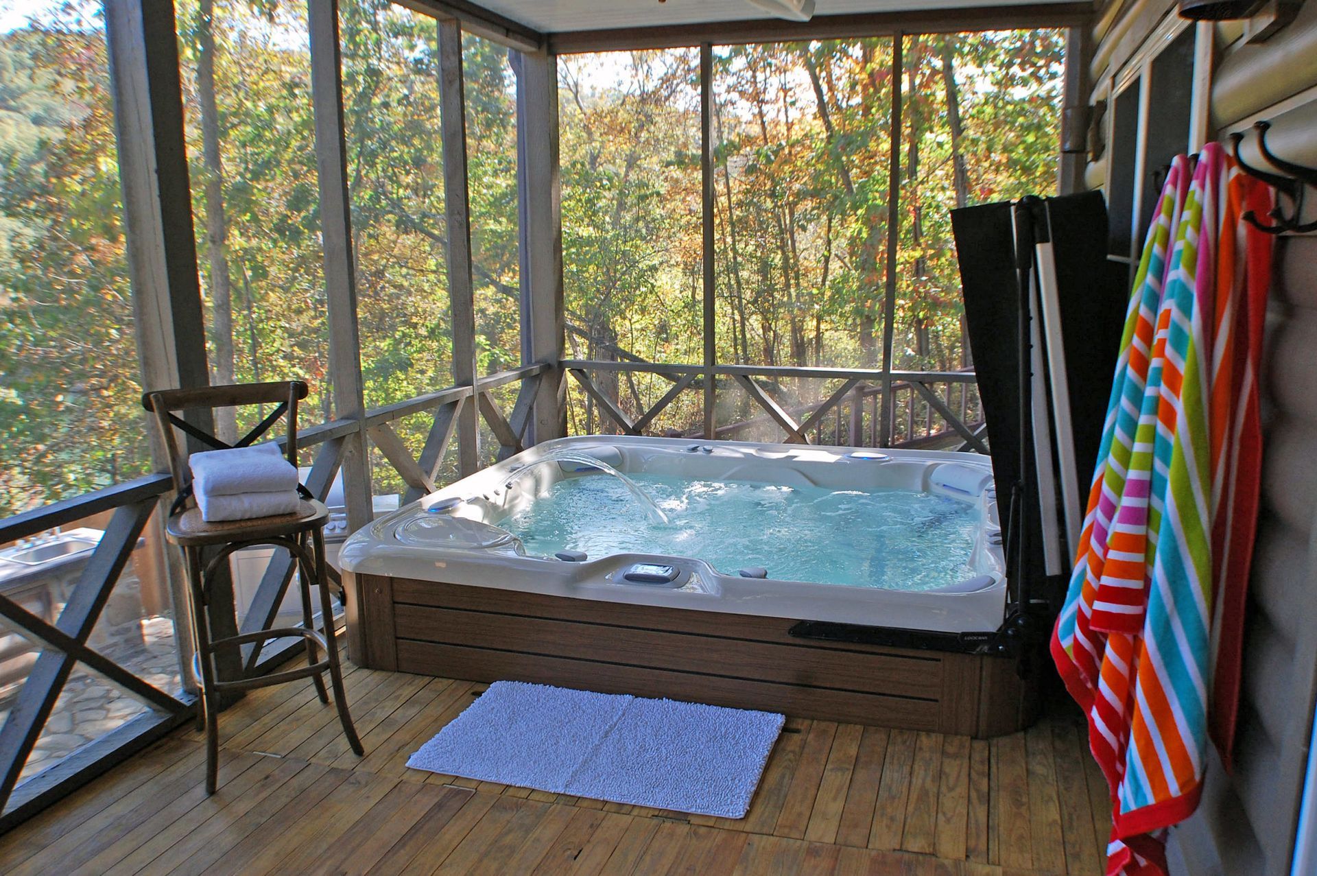 A screened in porch with a hot tub and towels