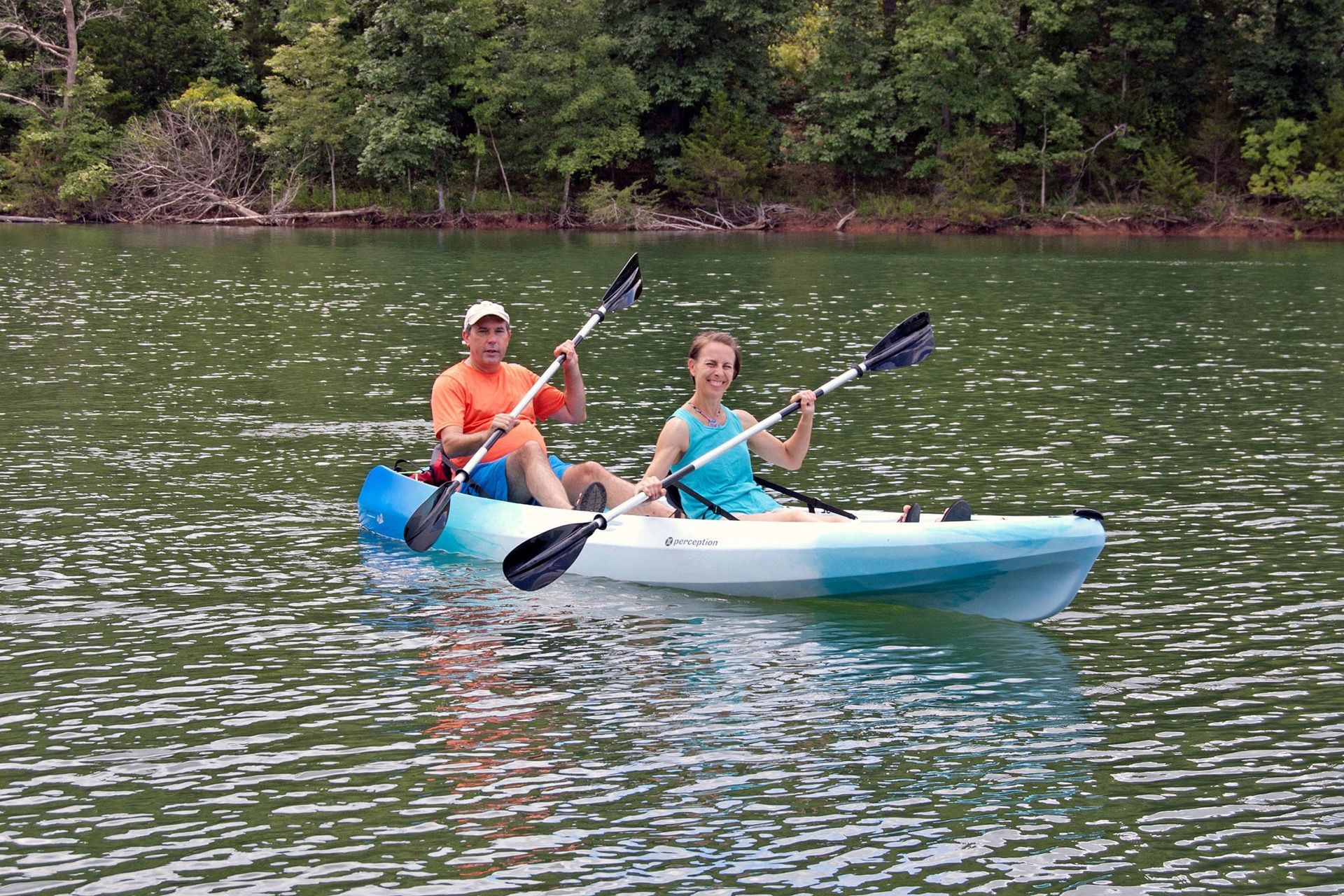 A man and a woman are paddling a kayak on a lake.