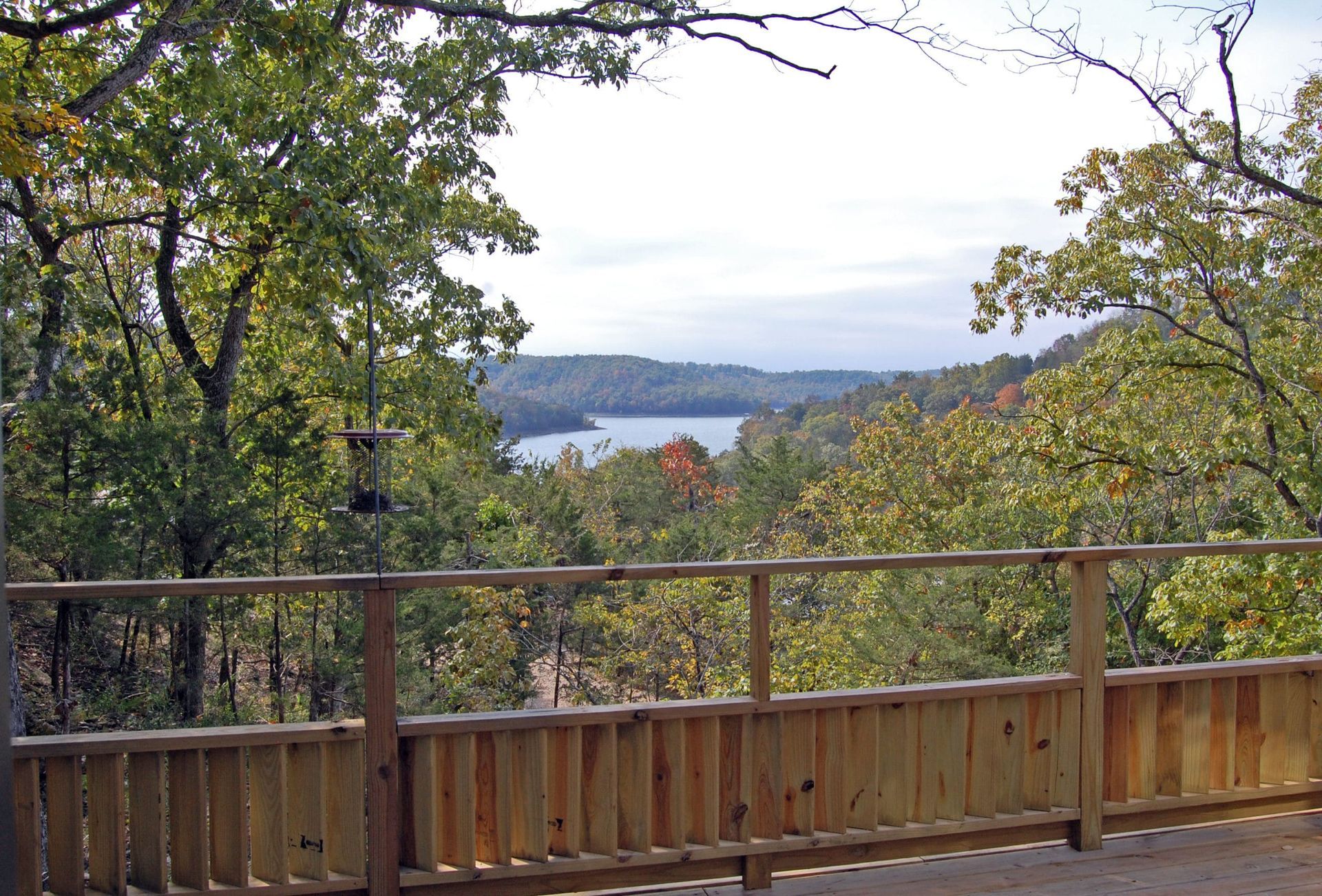 A wooden deck overlooking a lake surrounded by trees