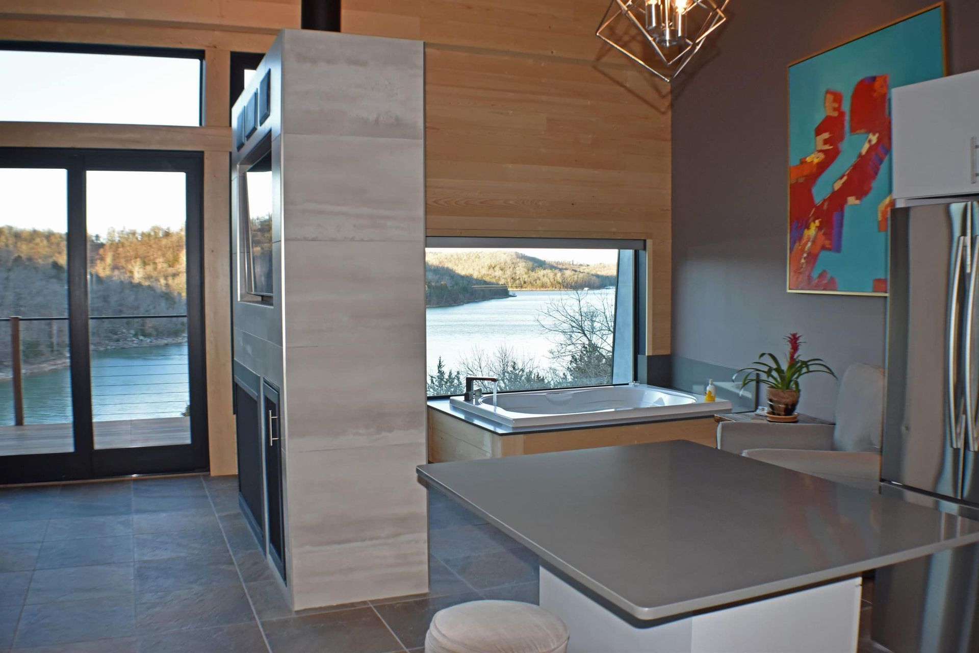 A kitchen with a jacuzzi and a large window overlooking a lake.