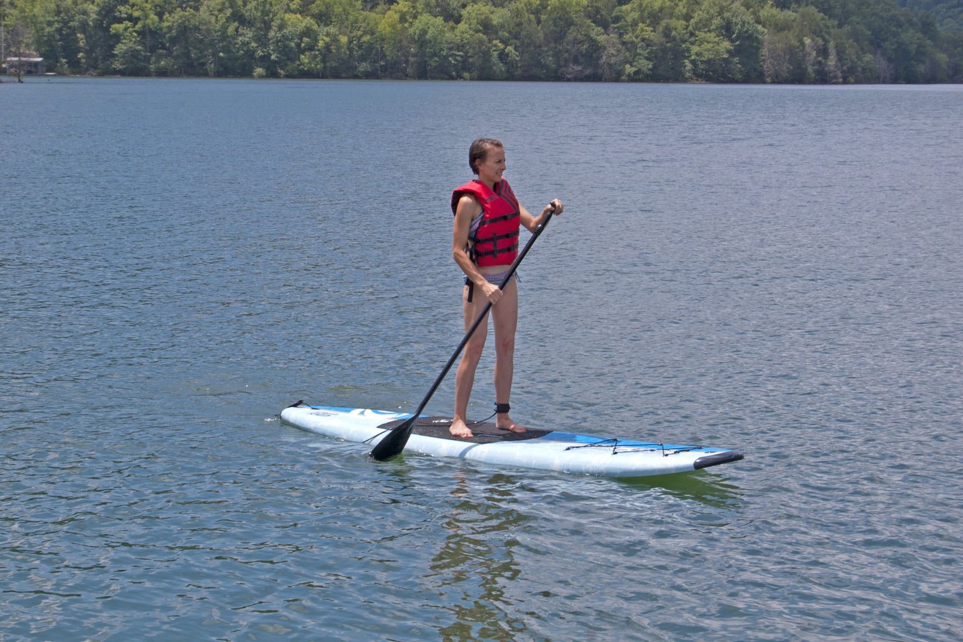 A person is standing on a paddle board in the water.