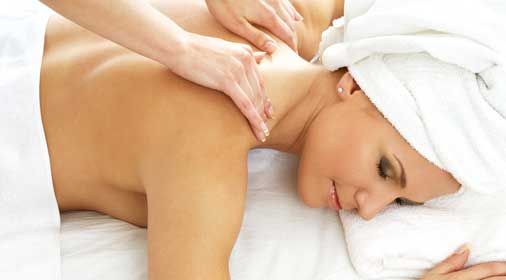 A woman with a towel wrapped around her head is getting a massage at a spa.