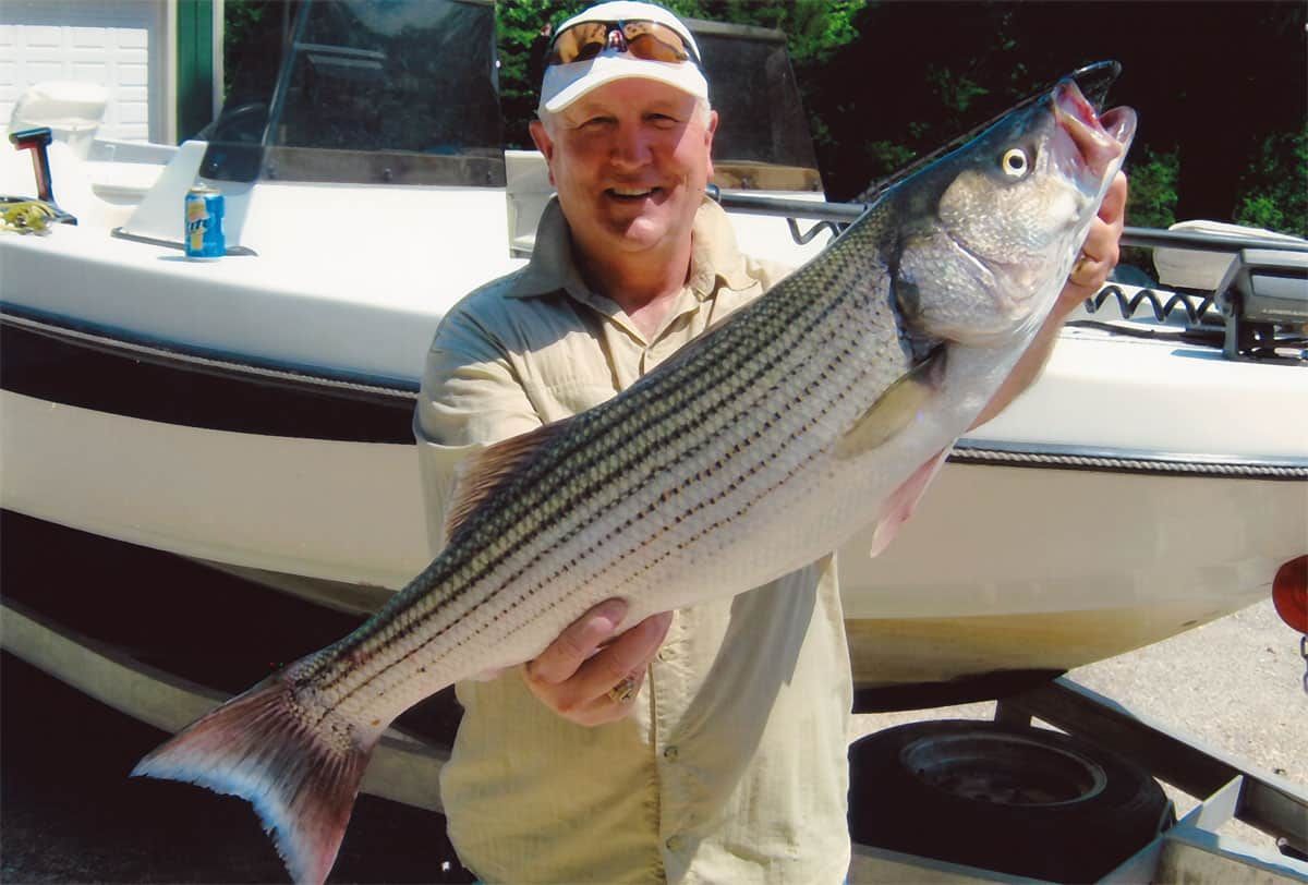 A man is holding a large fish in front of a boat