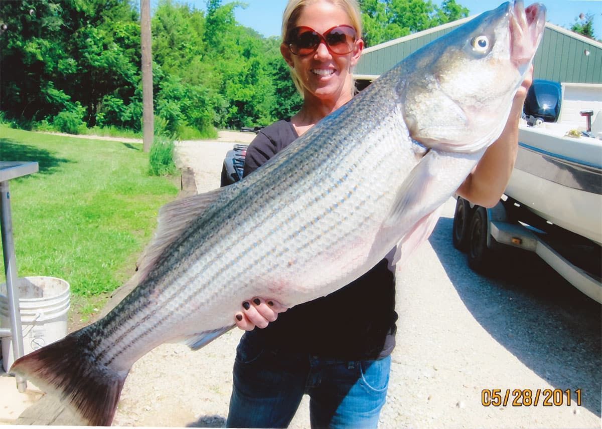 A woman is holding a large fish with the date 5/20/2011
