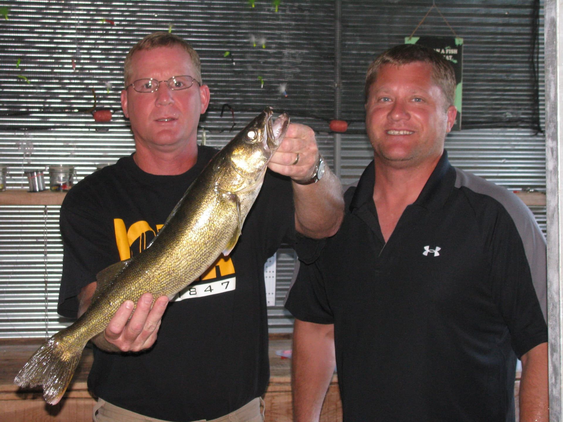 Two men standing next to each other holding a large fish