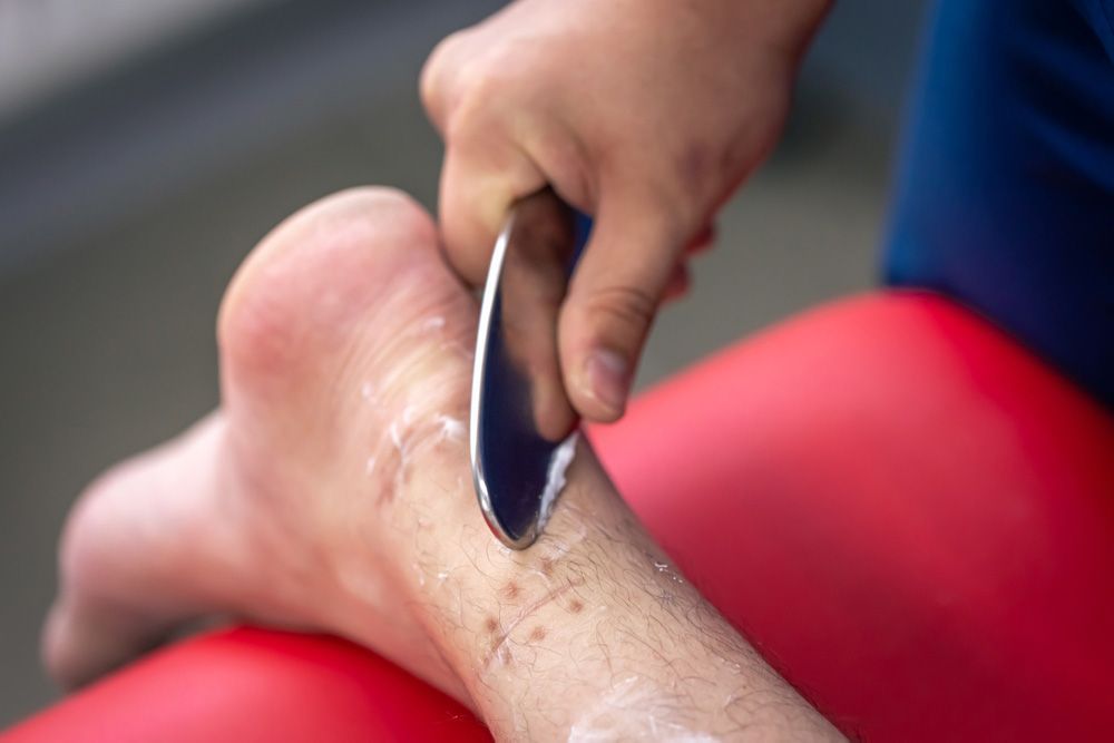 Doctor examines a young man's elbow. He wears white and smiles. Indoors, hands close-up.