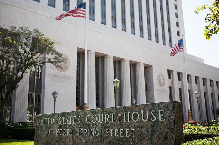 U.S. courthouse with white columns, American flags, and a stone sign at the entrance