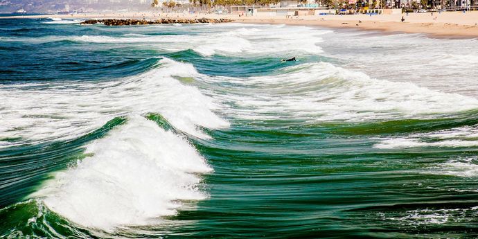 A tranquil river scene with a wooden bridge, framed by trees under a muted sky.