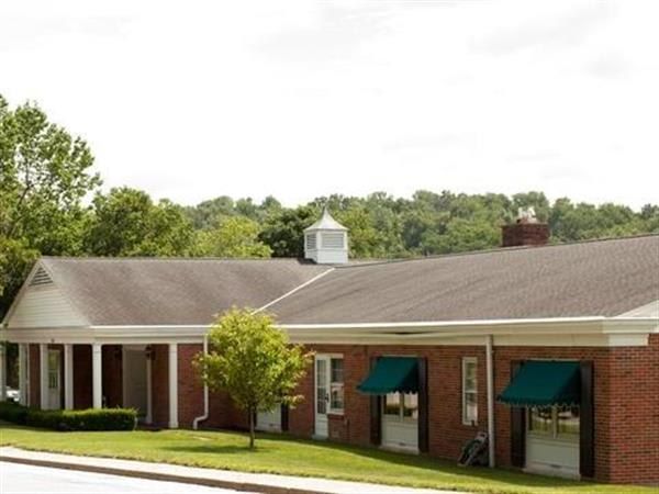 A brick building with a brown roof and green awnings