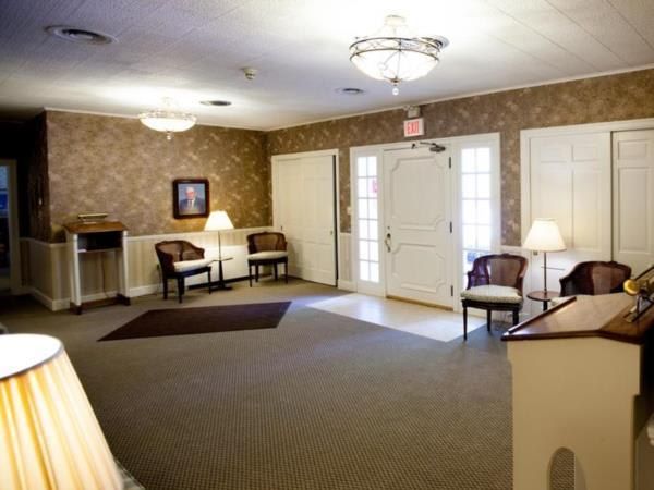 A living room with chairs lamps and a piano