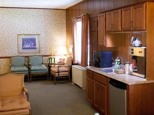 A living room with wood paneling and a kitchen