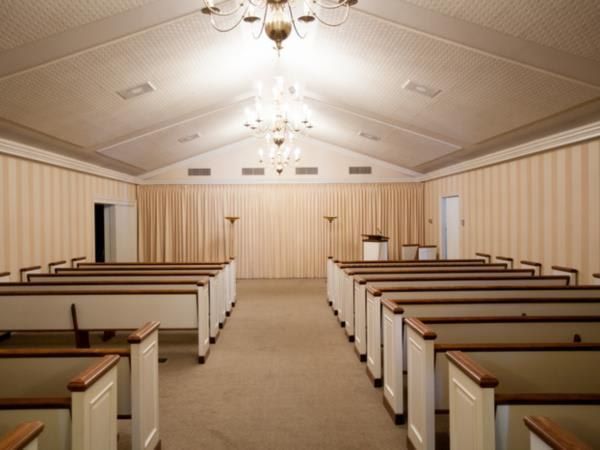 An empty church with rows of pews and a chandelier
