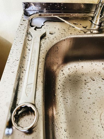 A wrench is laying on a stainless steel sink