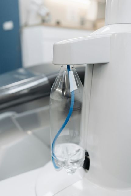 A plastic bottle with a blue ribbon attached to it