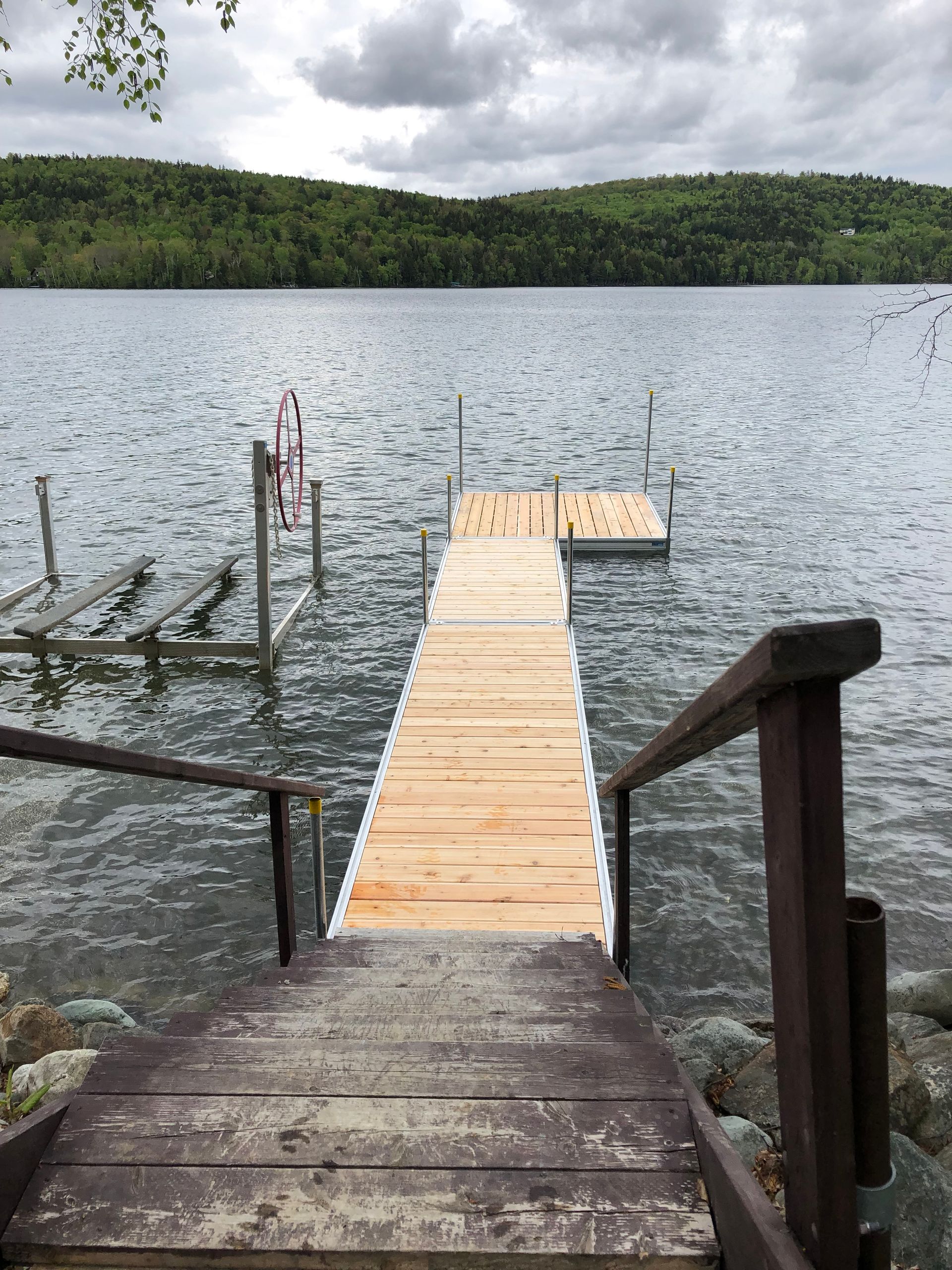 A wooden dock with stairs leading to a lake.