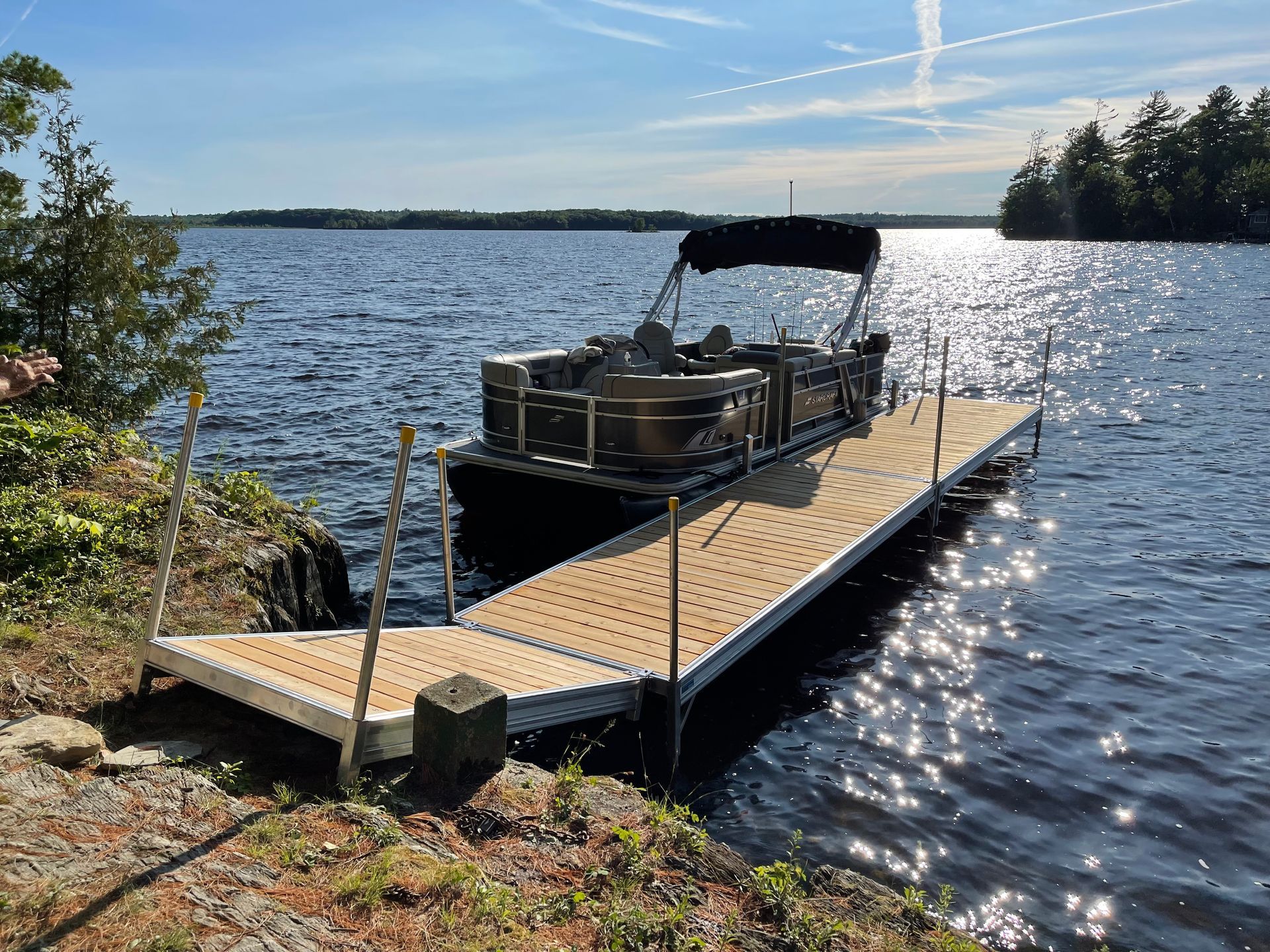 A pontoon boat is docked at a dock on a lake.