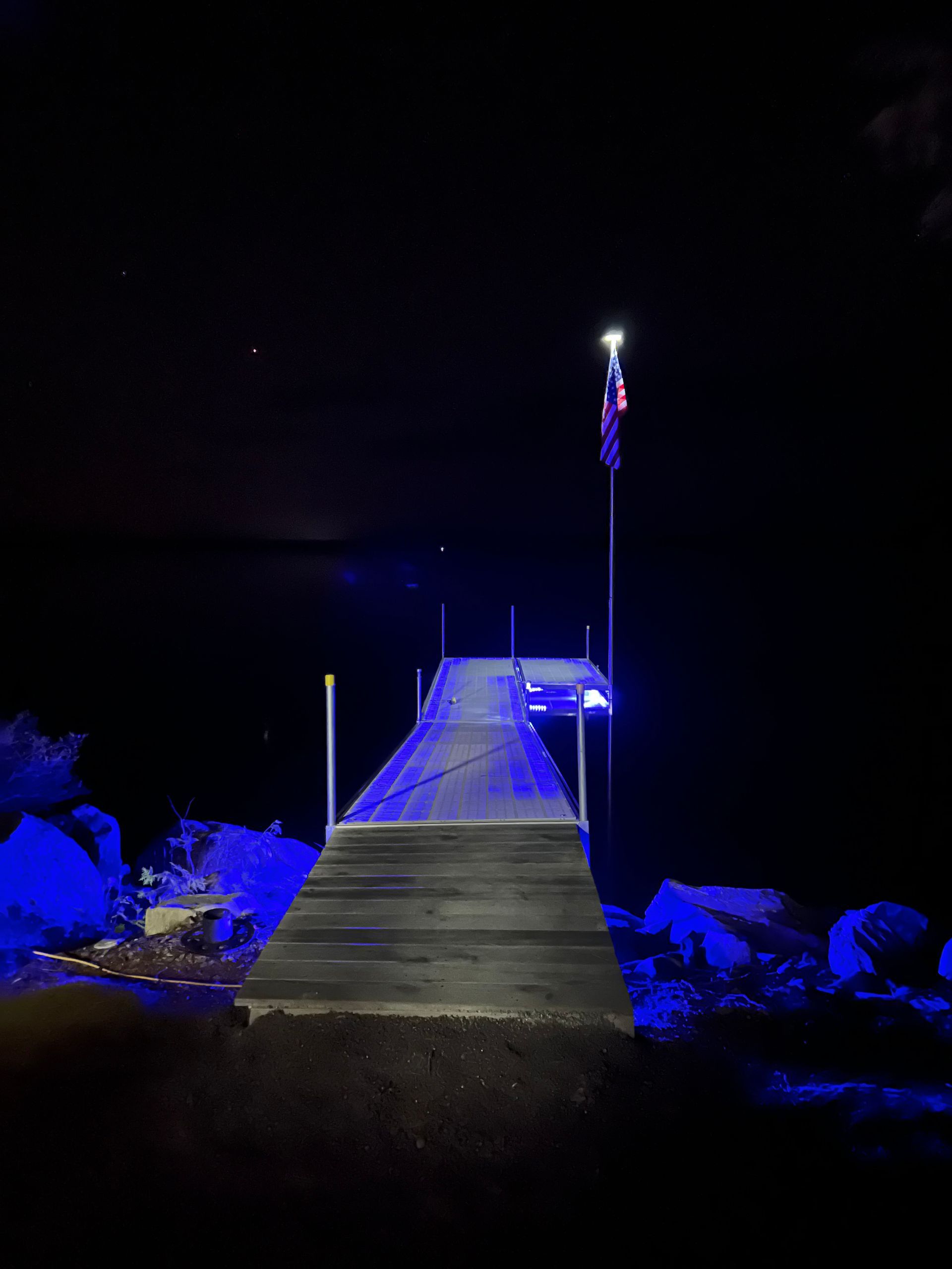 A dock is lit up with blue lights at night.