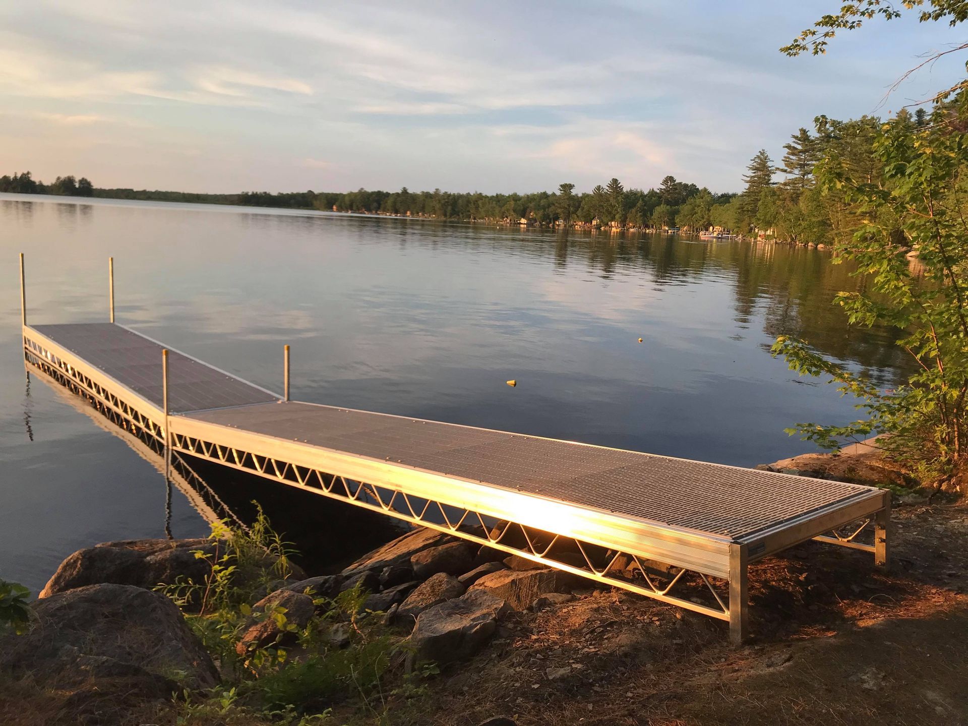 A dock on the shore of a lake with trees in the background