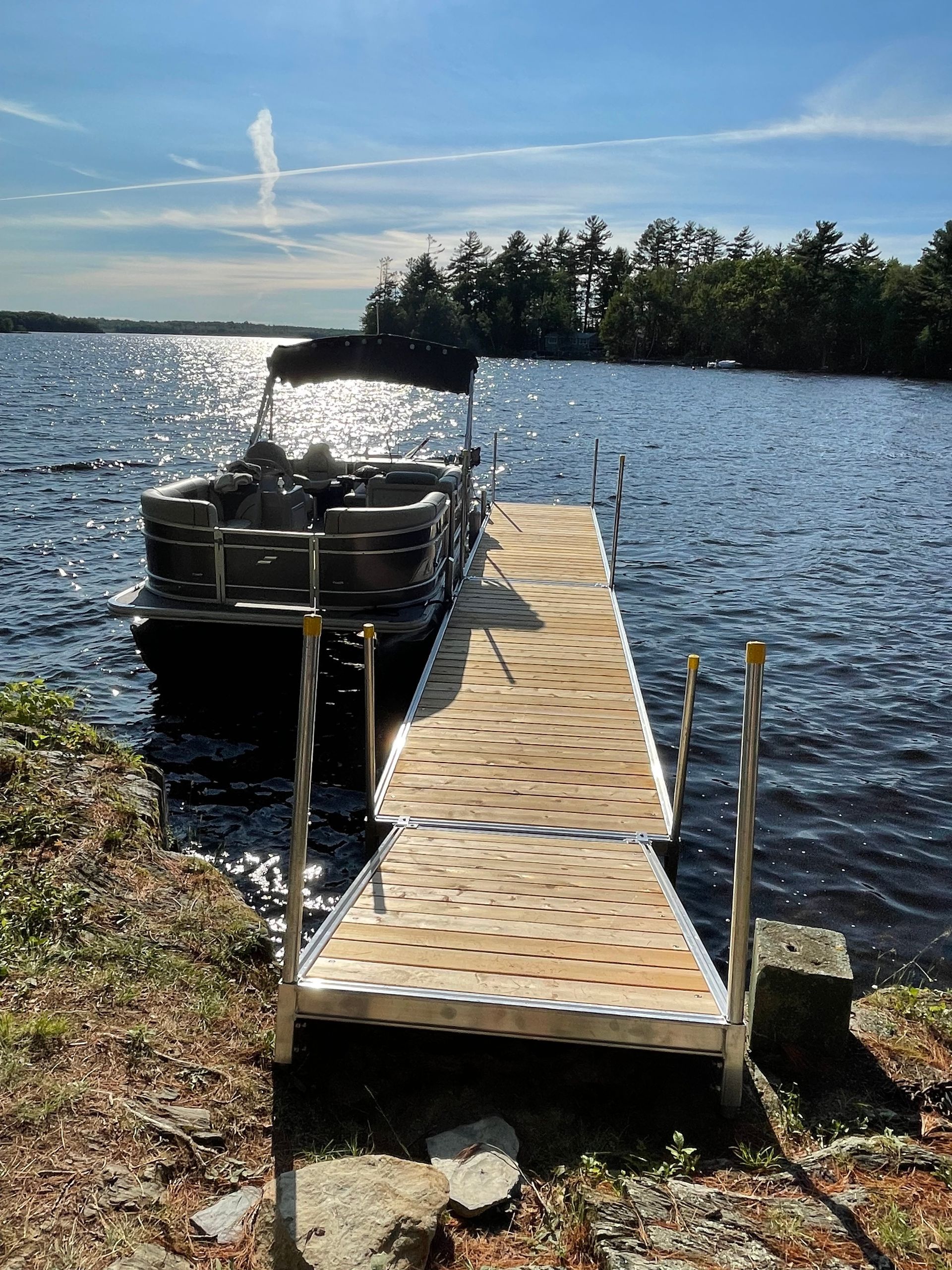 A pontoon boat is docked at a dock on a lake.