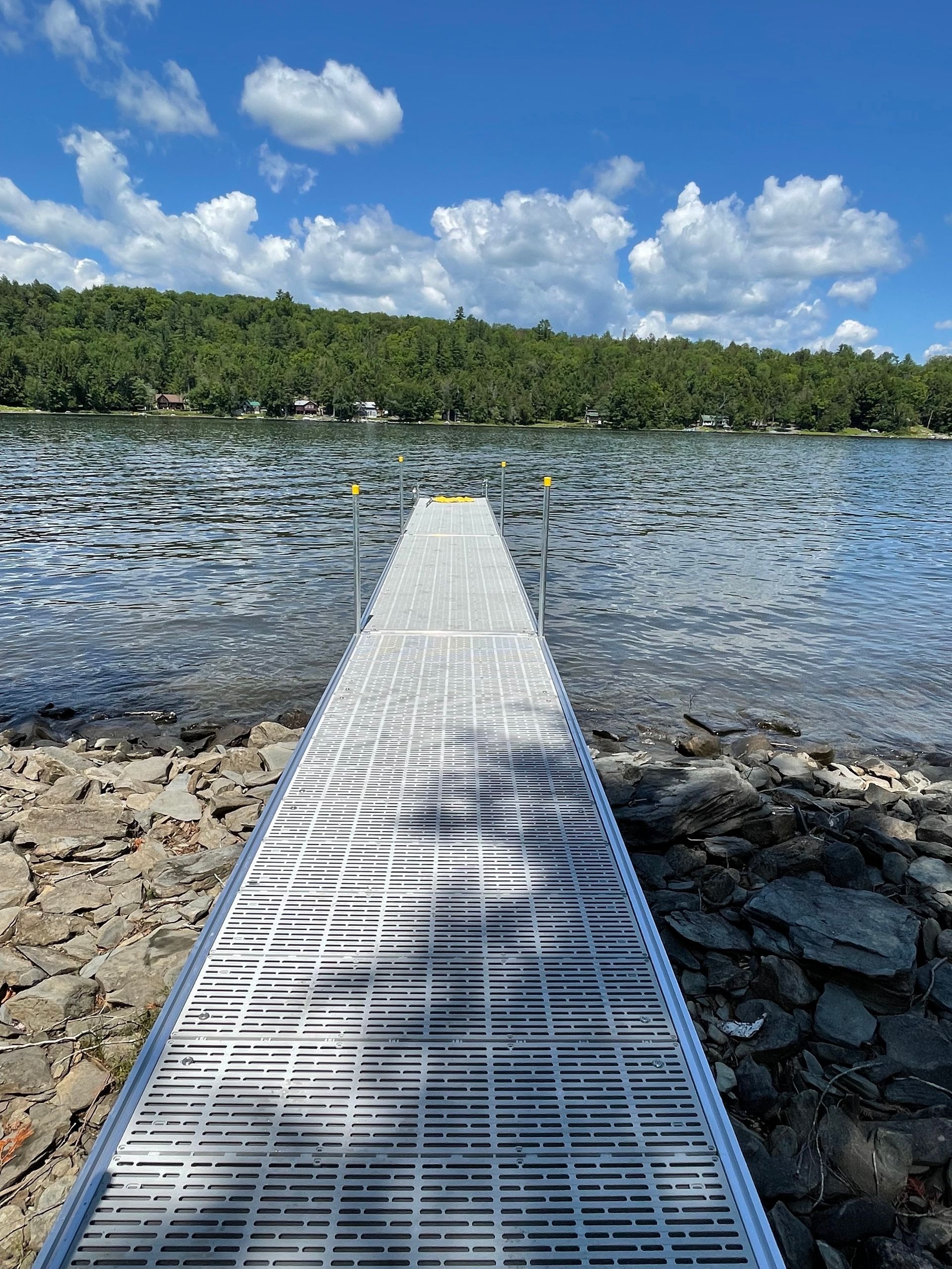 A dock leading into a lake on a sunny day.