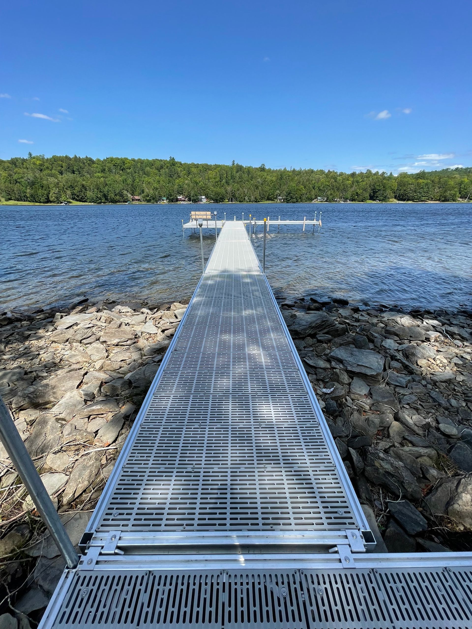 A dock leading into a lake with a boat in the water.