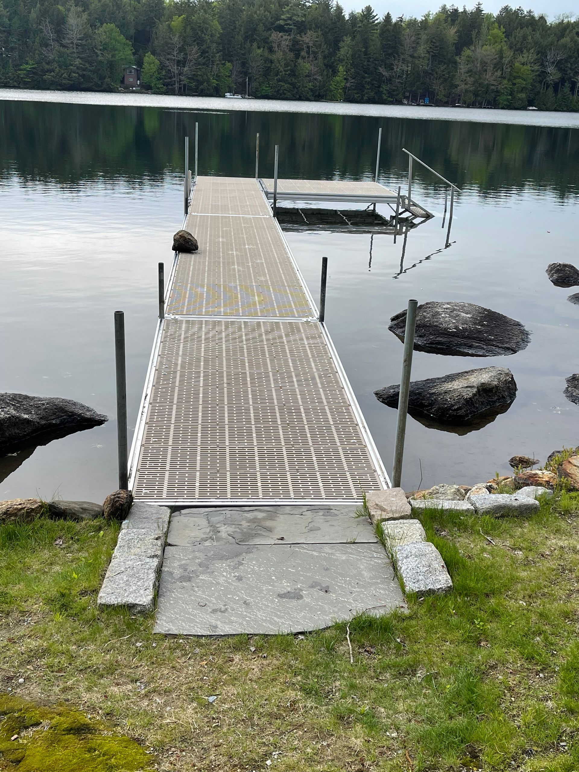 A dock in the middle of a lake with trees in the background