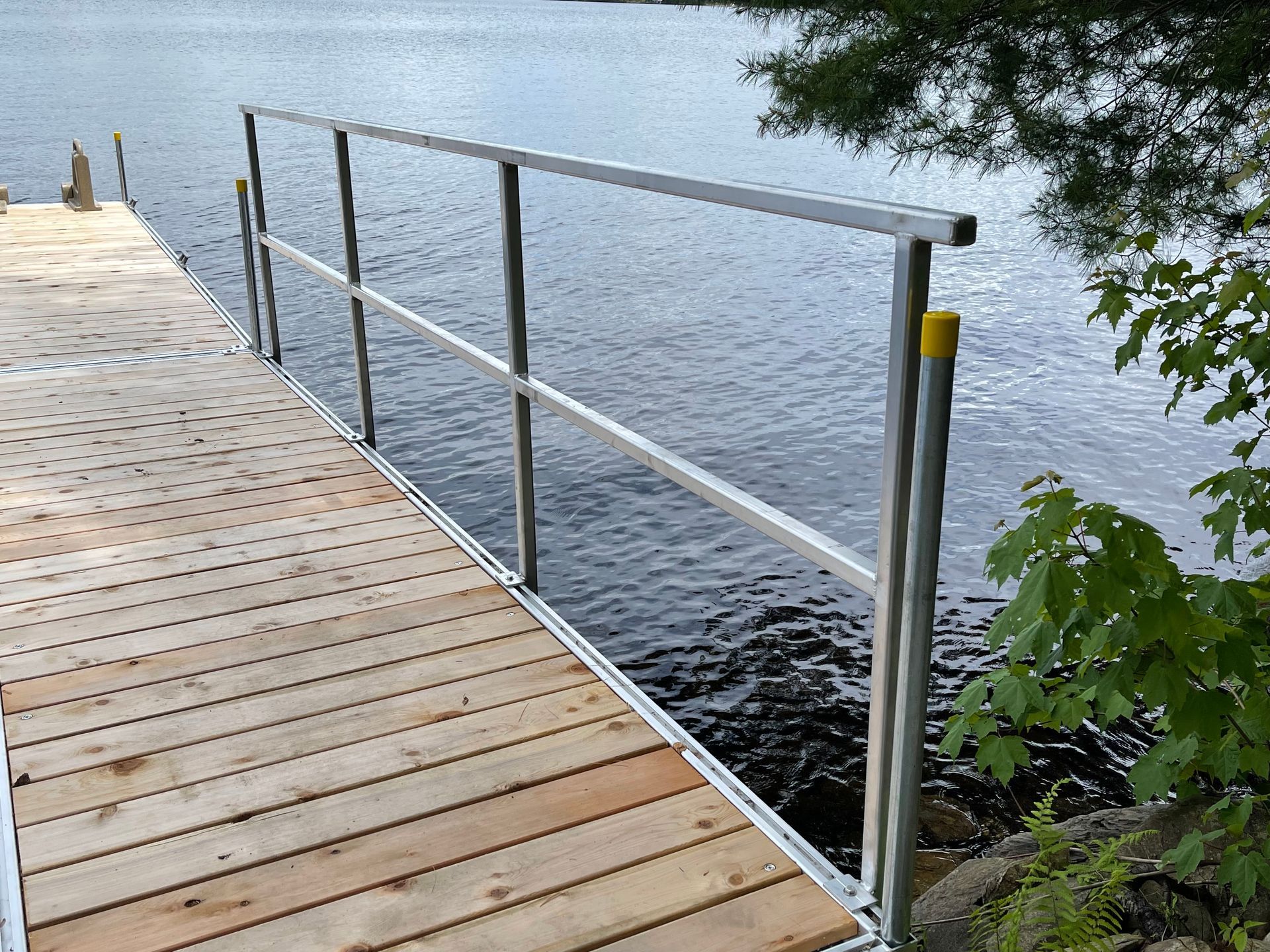 A wooden dock with a metal railing leading to the water.