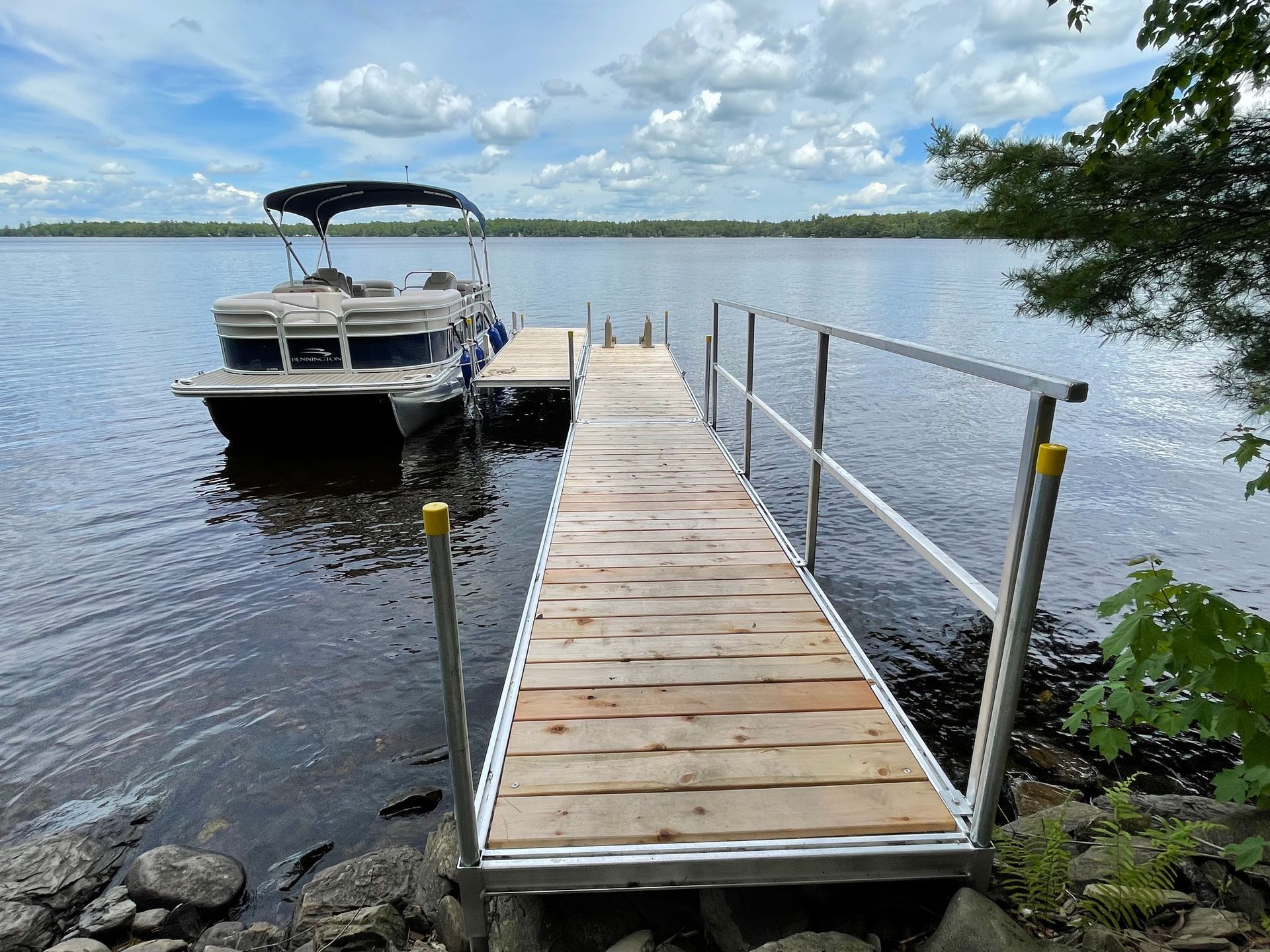 A pontoon boat is docked at a dock on a lake.